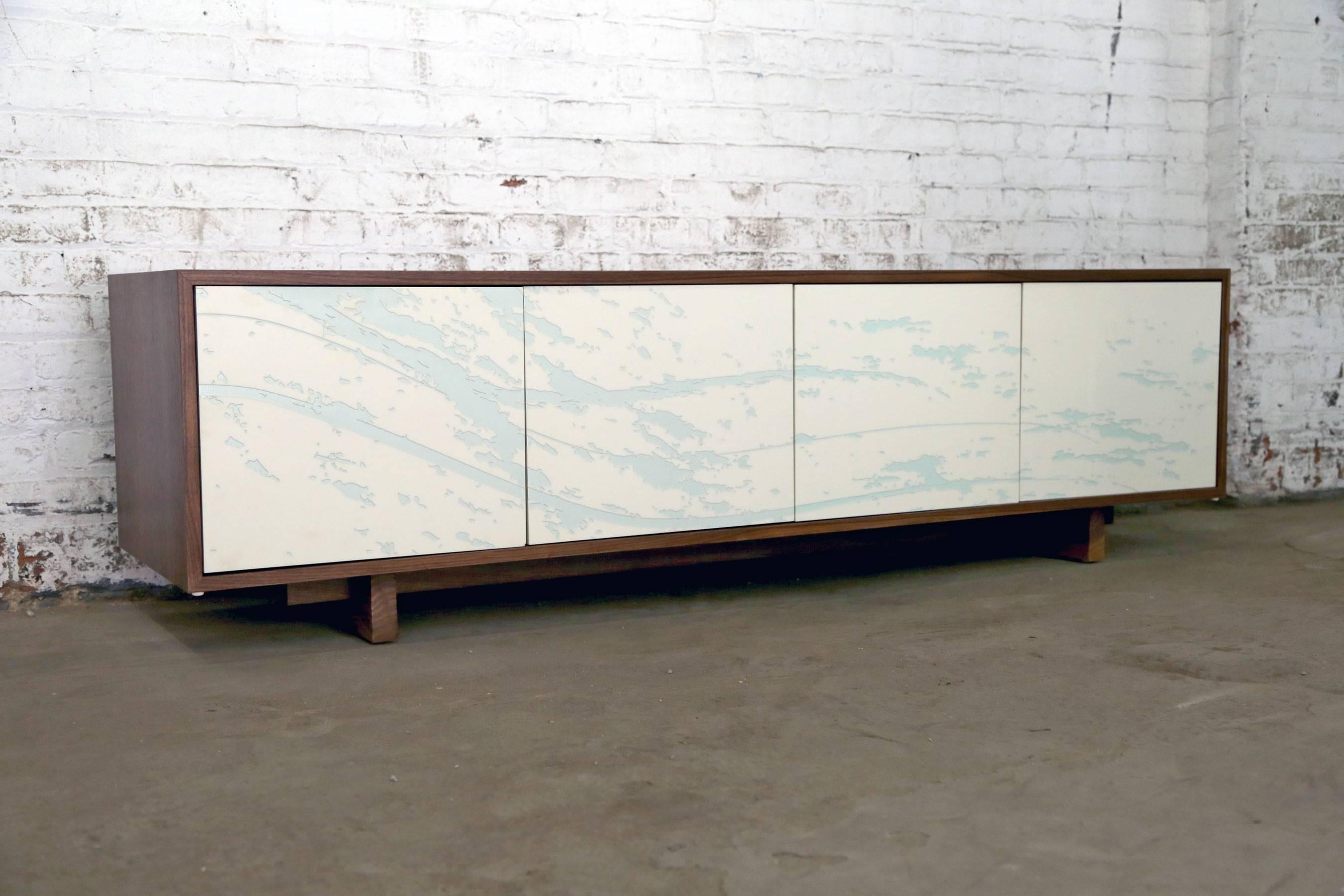 This credenza features four doors with laser-engraved custom art with an inlay. The cabinet opens to store anything from stereo equipment to service ware. Inside there is adjustable shelving. The cabinet is made using locally-sourced hardwoods,