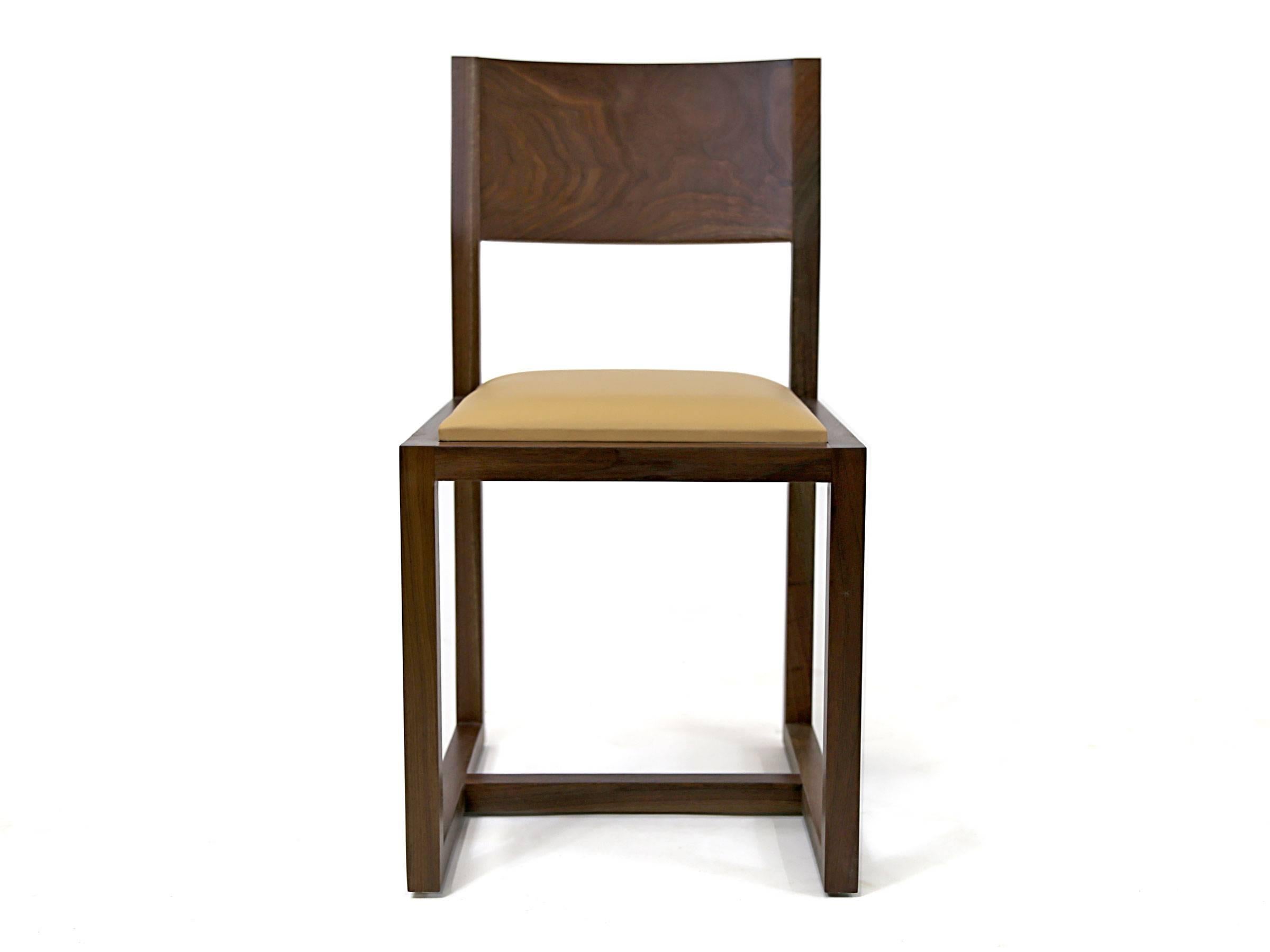A contemporary hardwood chair with curved back made from solid wood, and an upholstered seat. A straightforward design. Simplicity incarnate. Made to order in Brooklyn. Shown in walnut with a tan leather seat. Other options are available. Discounts