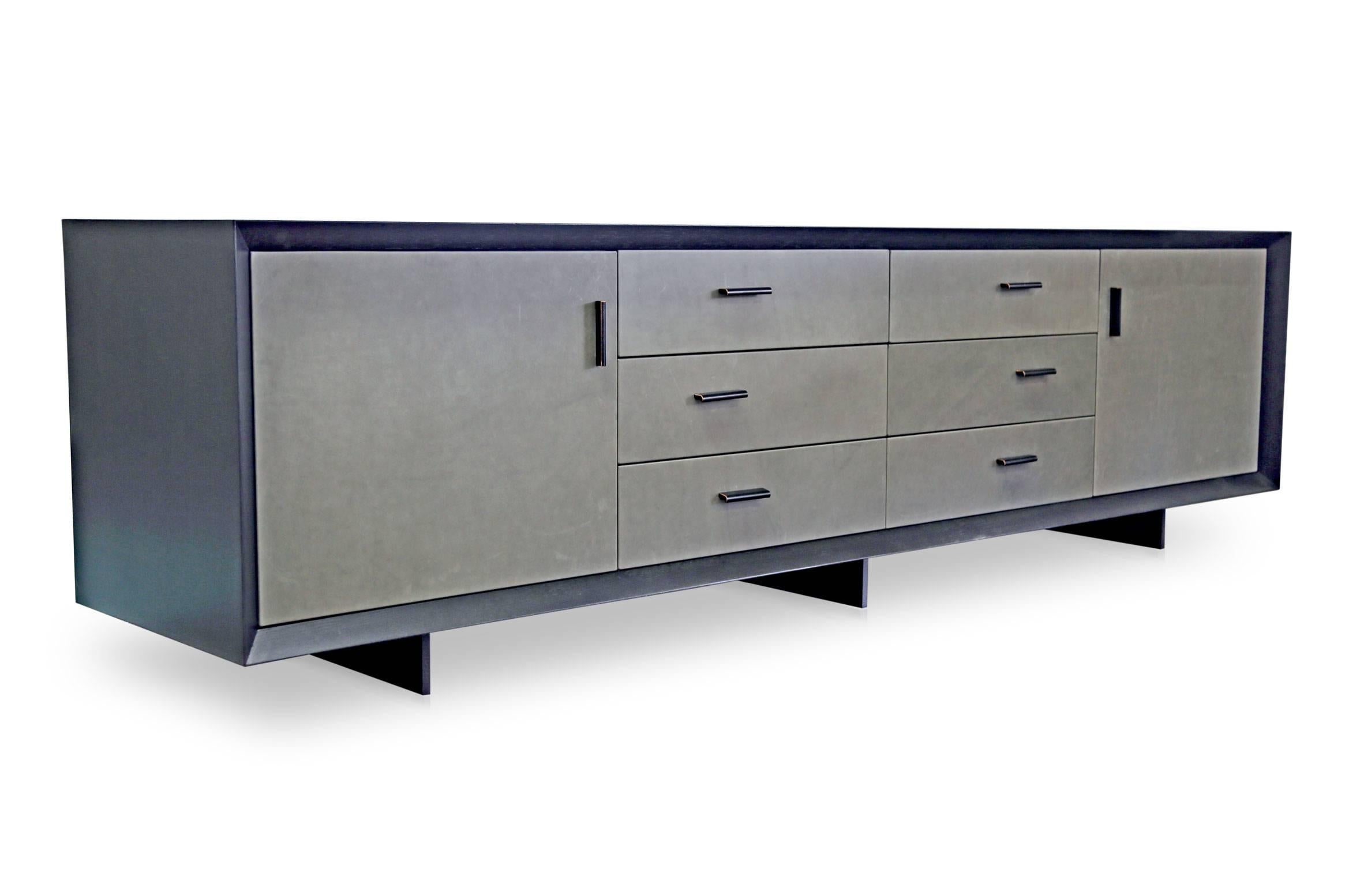 The Sentient Murlough dresser is a refined storage piece in sleek, muted tones of black and grey. Each dresser is handmade to order in Brooklyn. The ebonized cabinet accentuates natural wood grains, and juxtaposed with the supple leather that wraps