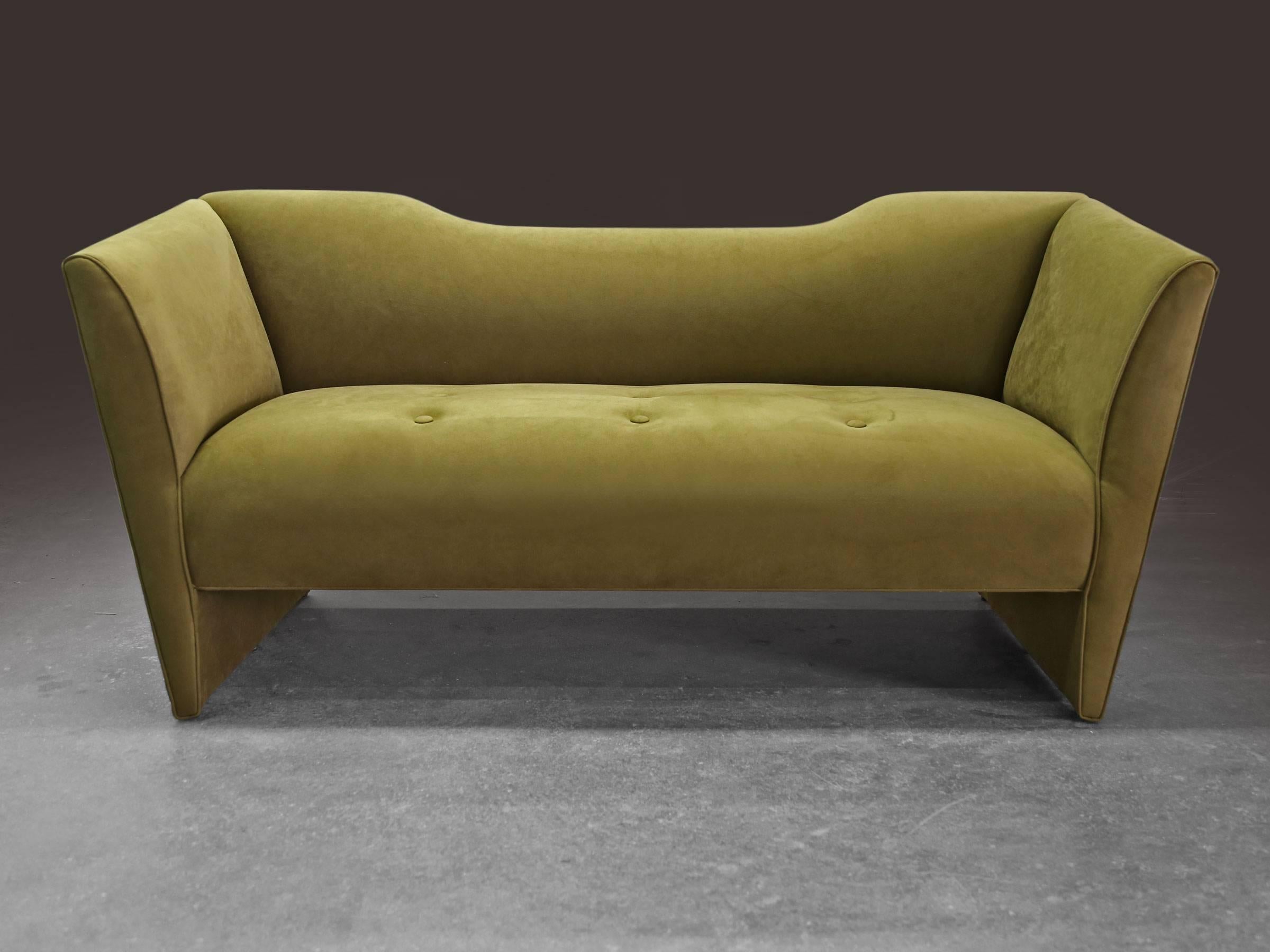 This unconventional sofa is completely covered in upholstery, all the way down to the legs. Its sensuous lines are refined and the seat, back and arms seem to leap upward and outward from the base for an attractive post modern Memphis-inspired
