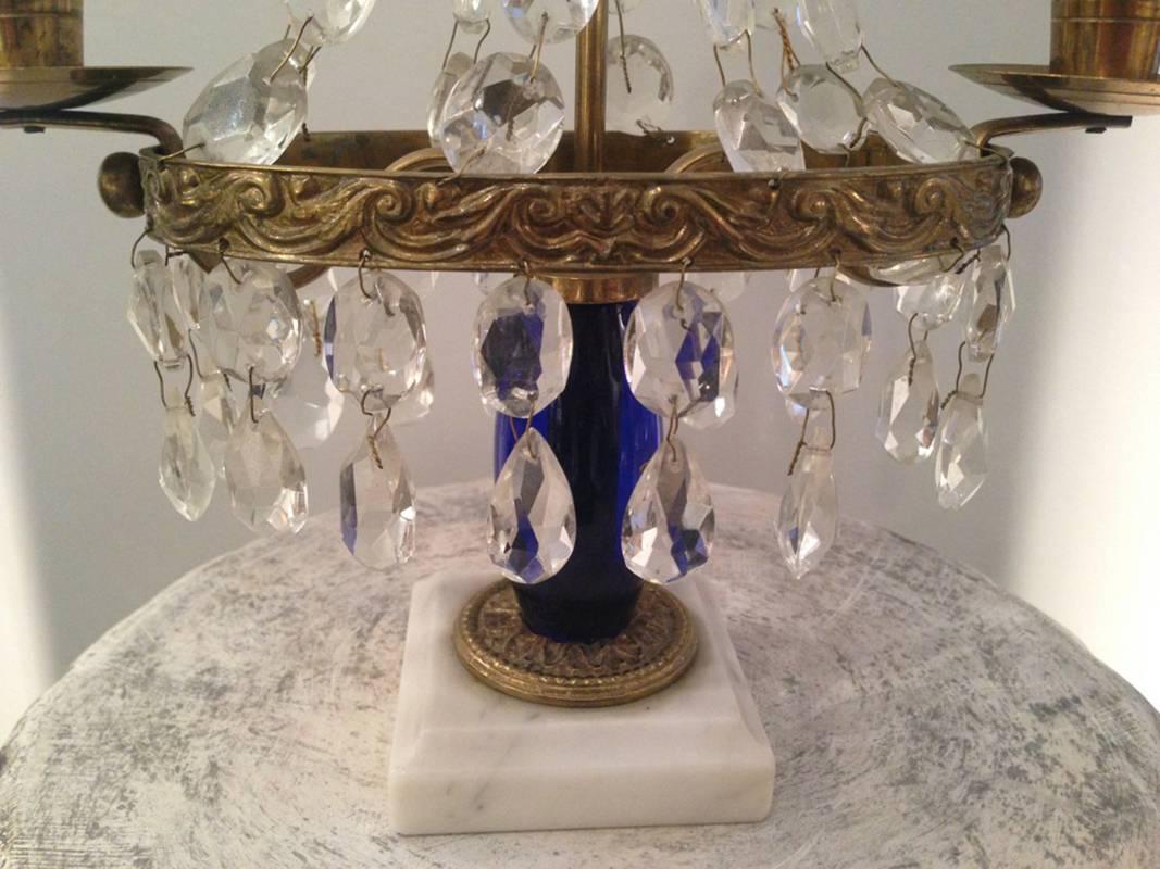 A pair of Swedish Gustavian Style girandoles with hanging crystals, cobalt blue glass body and a white marble base.