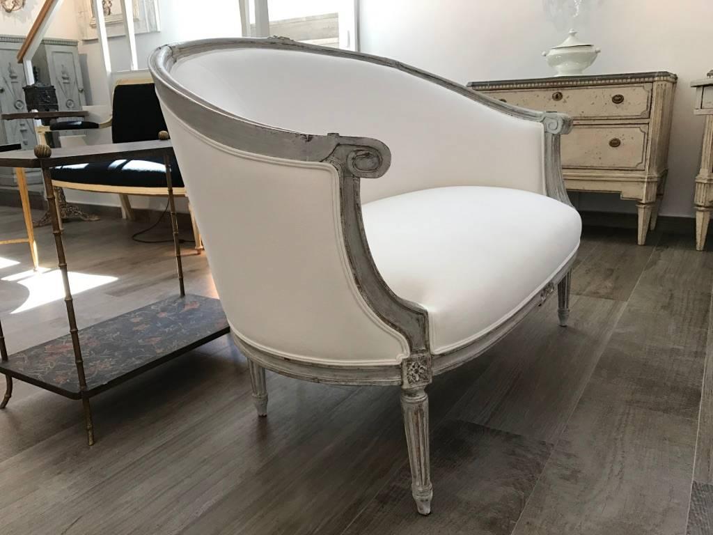 French Louis XVI style corbeille canapé from the 19th century, in carved wood with later paint. Newly reupholstered in white plain linen and cotton fabric.
