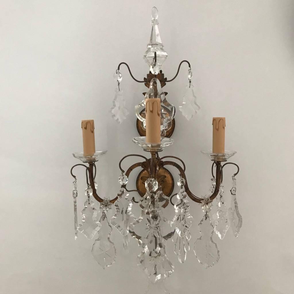 Stunning set of four Italian wall lights from 1900. They have three arms gilded brass, glass bobeches and original antique crystal faceted pendants, hand carved and completely transparents. Fully rewired. 