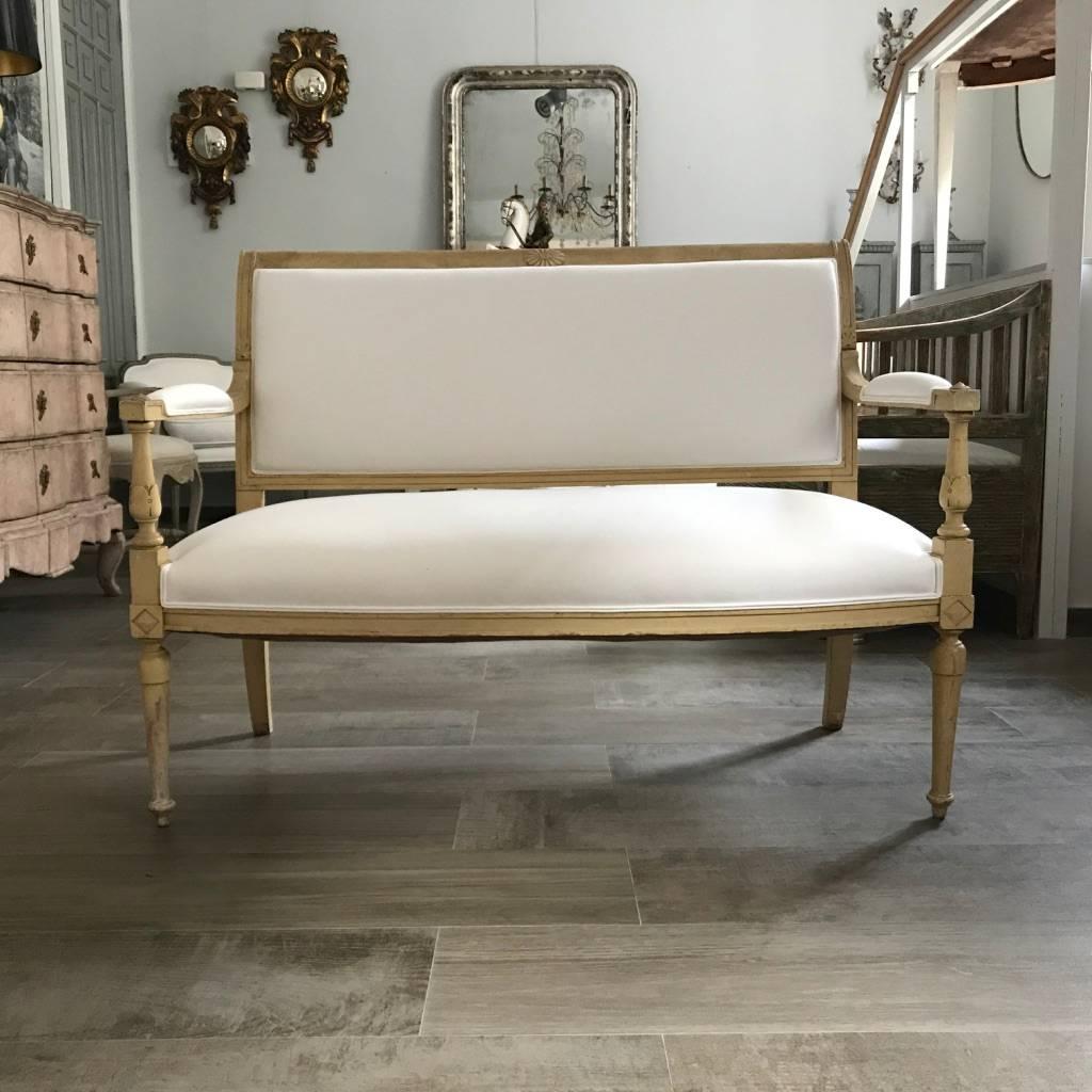 Charming French Directoire style canapé with its original patina and beautifully carved. It has been reupholstered in a white natural 100% cotton fabric.