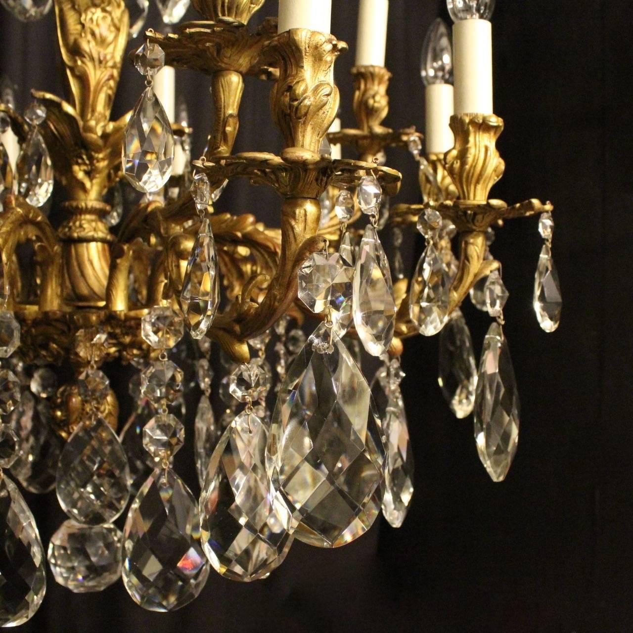 An Italian gilded cast bronze and crystal fifteen-light double tiered antique chandelier, the ornate acanthus leaf scrolling arms with pierced leaf bobeche drip pans and bulbous candle sconces, issuing from a foliated twisted bulbous central column