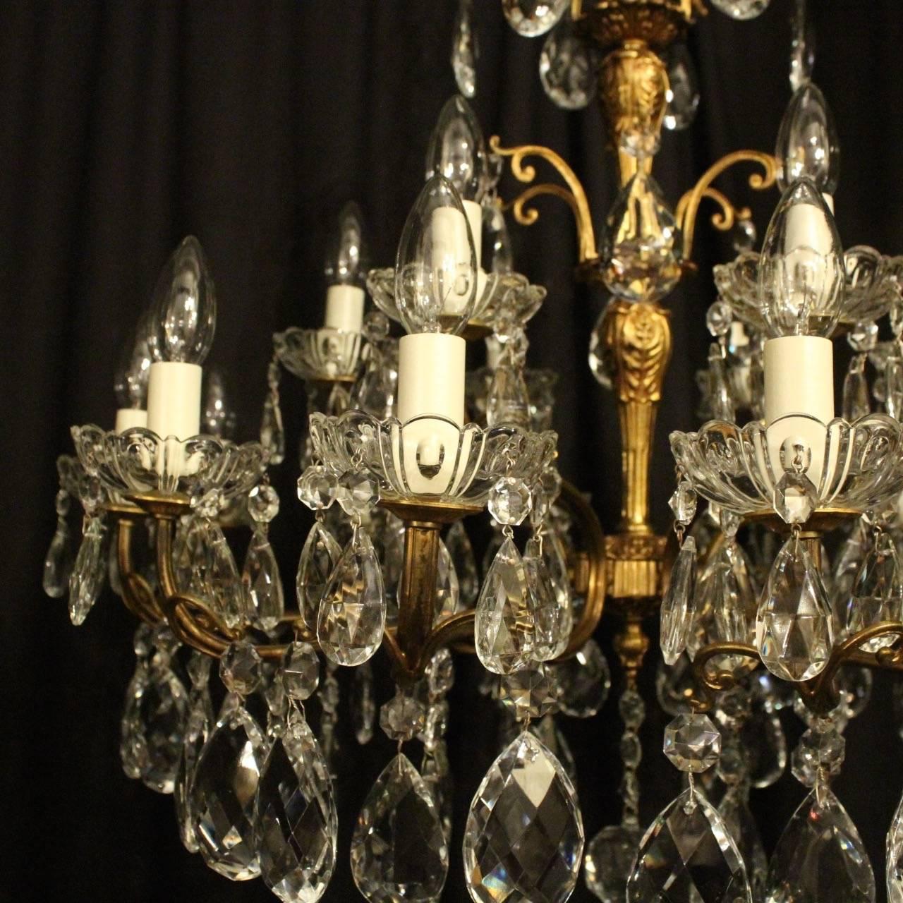 An Italian gilded cast brass and crystal cut-glass eighteen-light double tiered antique chandelier, the scrolling arms with ornate outcrops and glass bobeches drip pans issuing from a foliated baluster central column with a scrolling mid and top