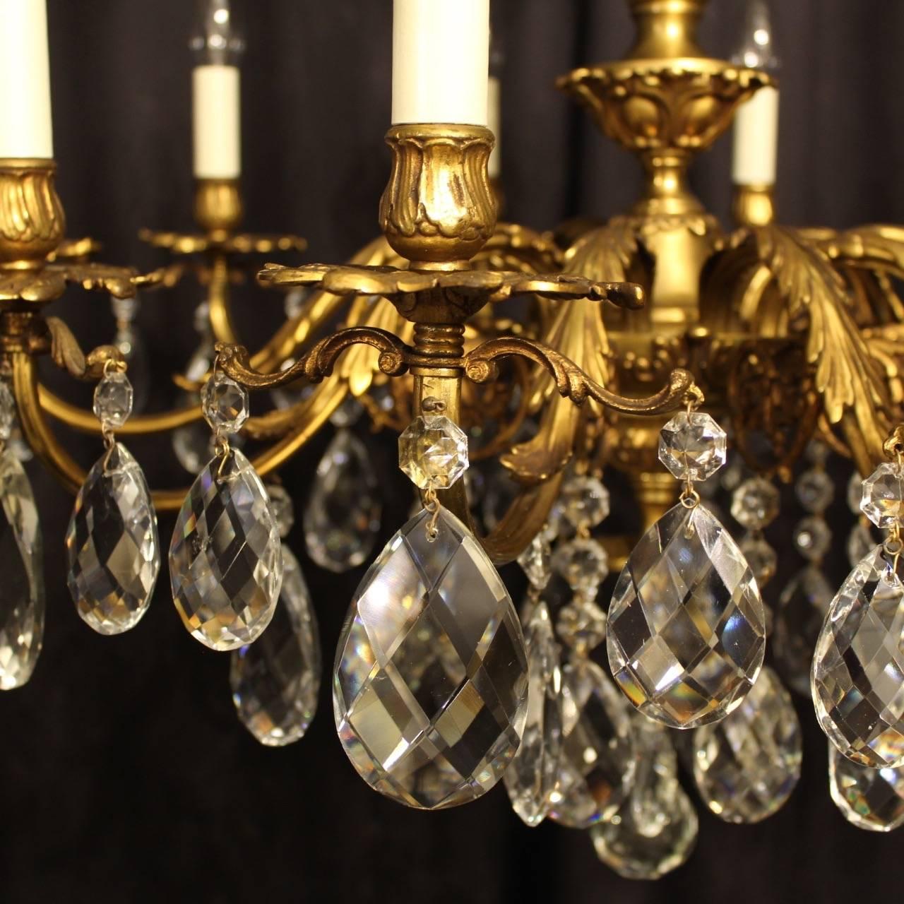 An Italian gilded cast brass and crystal ten-light antique chandelier, the ornate scrolling arms with pierced leaf bobeche drip pans and bulbous candle sconces, issuing from a tapering central column and ornate central pierced leaf embellishment and