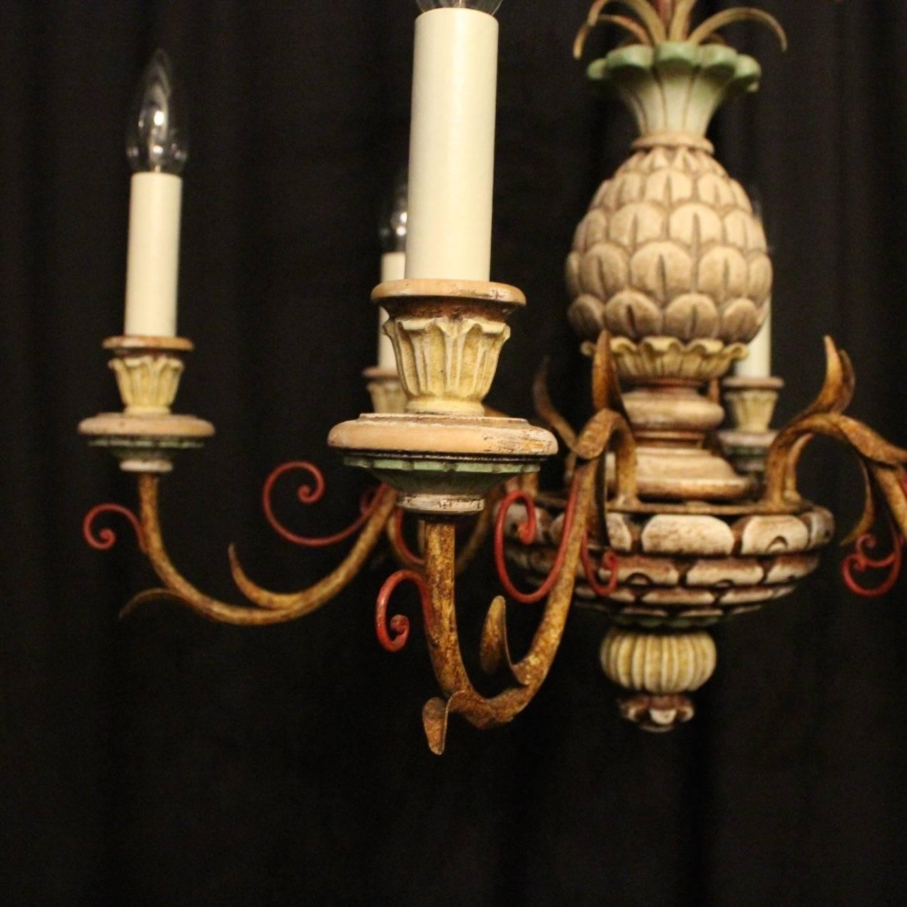 A decorative French polychrome six-light chandelier, the gilded metal leaf scrolling arms with wooden reeded bulbous candle sconces, issuing from a wooden pineapple baluster central column with wheat sheaf wirework canopy, having the original chain