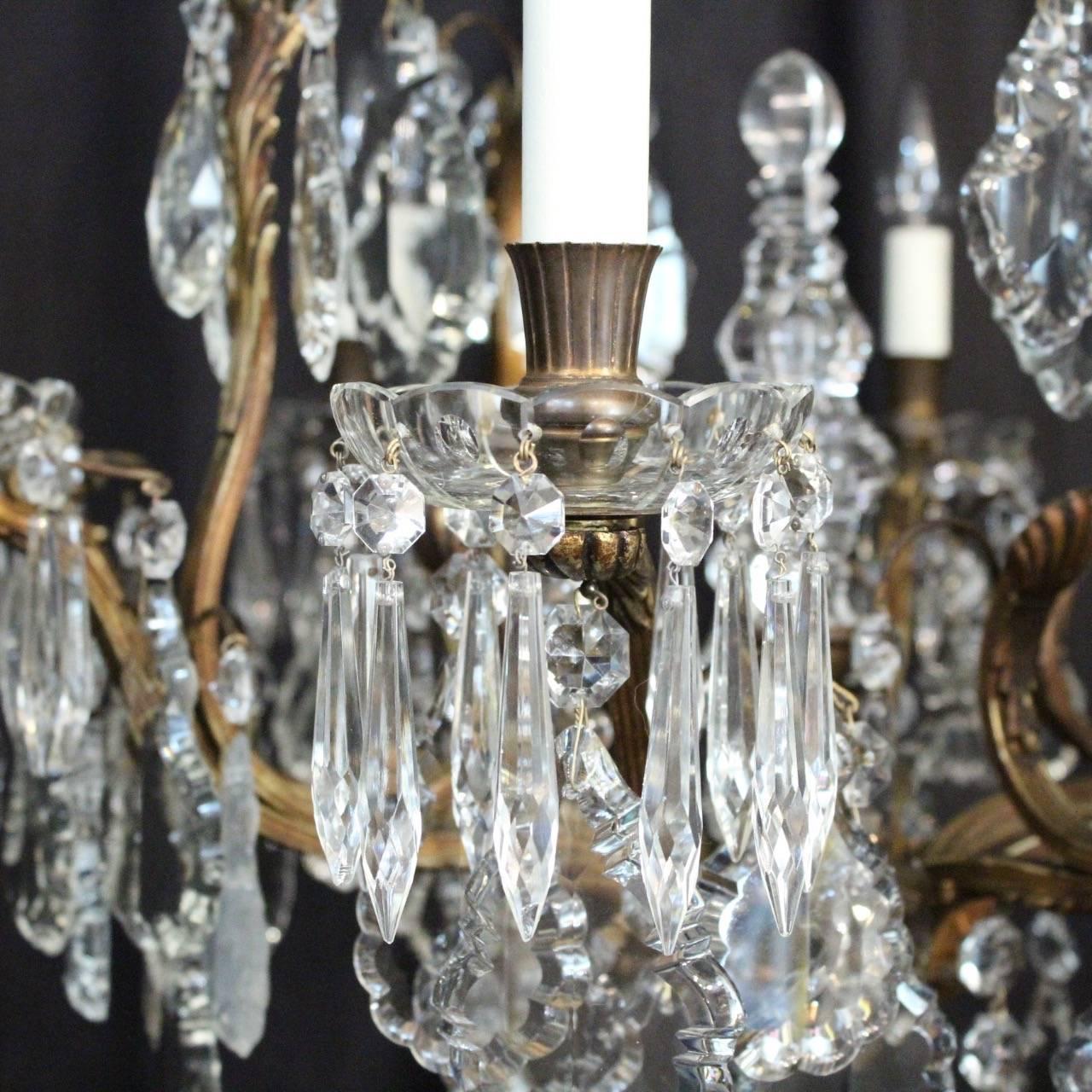 A French gilded cast bronze and crystal nine-light birdcage form antique chandelier, the reeded scrolling arms with glass bobeche drip pans and reeded candle sconces, issuing from a foliated cage form interior with a single inverted light fitting