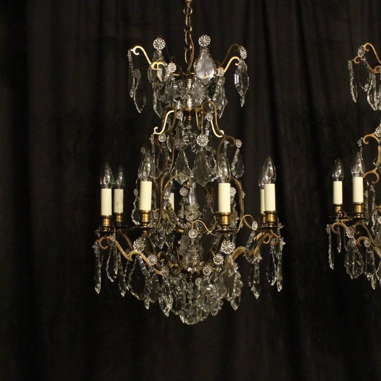 A French pair of gilded brass and crystal eight-light birdcage form antique chandeliers, the square gauge scrolling arms with floral bobeche drip pans and bulbous candle sconces, issuing from a cage form interior with a large prismatic spike and an