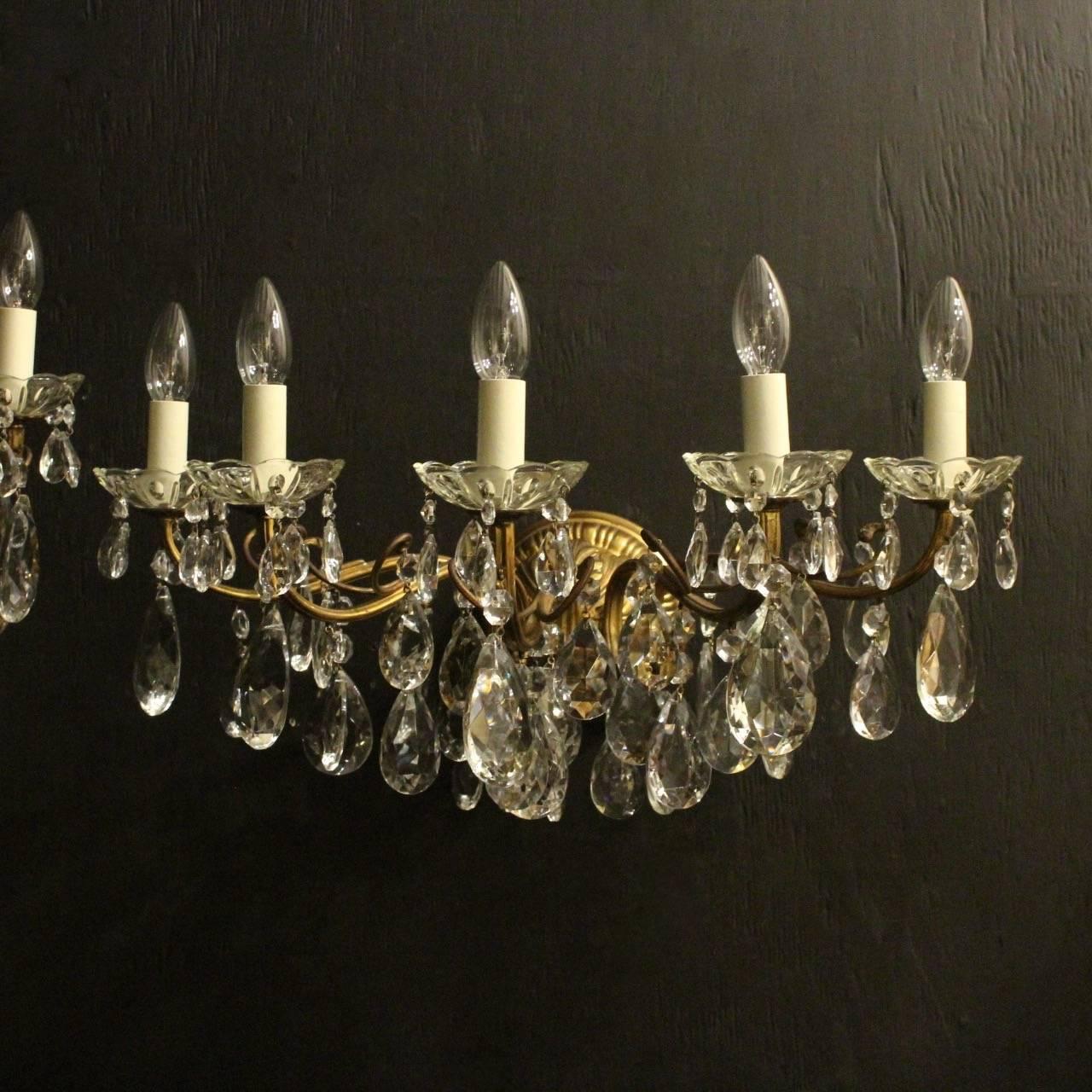 A very large Italian pair of gilded cast brass and crystal five-arm antique wall lights, the leaf scrolling arms with glass bobeche drip pans, issuing from a foliated circular backplate and decorated overall with cut-glass crystal faceted pendants,