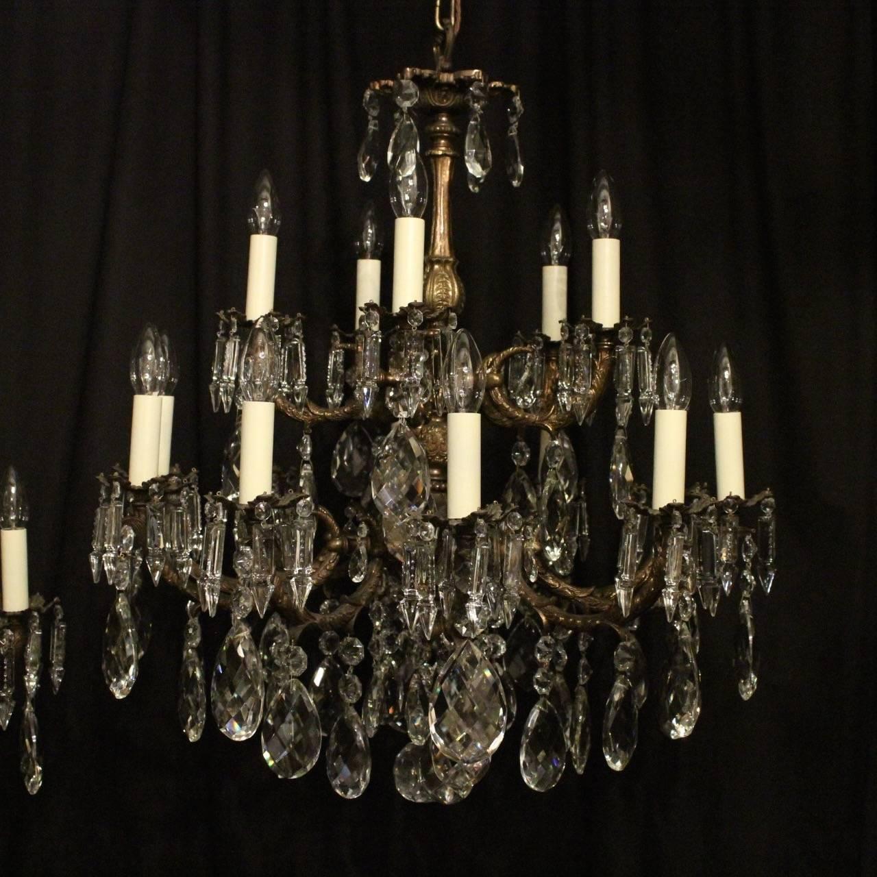 An Italian pair of gilded cast brass and crystal fifteen-light double tiered antique chandeliers, the scrolling arms with ornate cast bobeche drip pans, issuing from a foliated cast baluster central column with foliated canopy and decorated overall