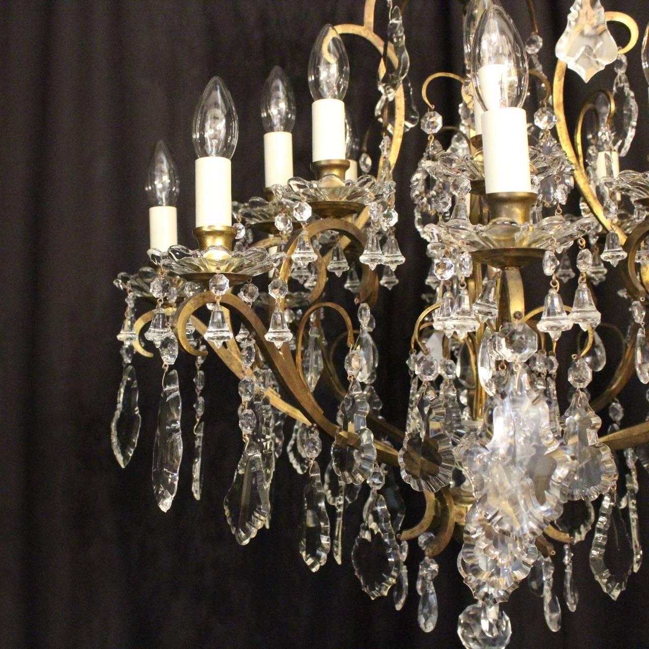 A large French cast brass and crystal sixteen-light birdcage form antique chandelier, the square gauge scrolling arms with foliated glass bobeche drip pans and candle sconces, issuing from a cage form interior and ornate wirework canopy with glass