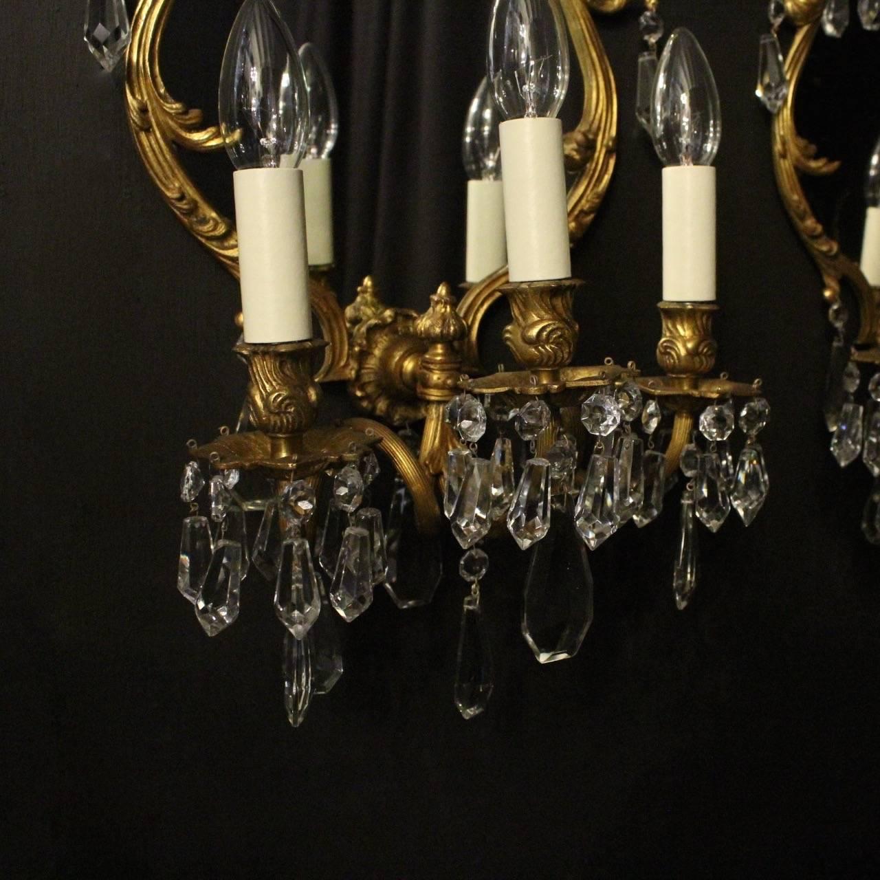 An ornate Italian pair of gilded cast bronze triple arm antique girandoles, the reeded scrolling arms with leaf bobeche drip pans and bulbous candle sconces, issuing from an ornately cast cartouche shaped mirrored backplate with central leaf motif