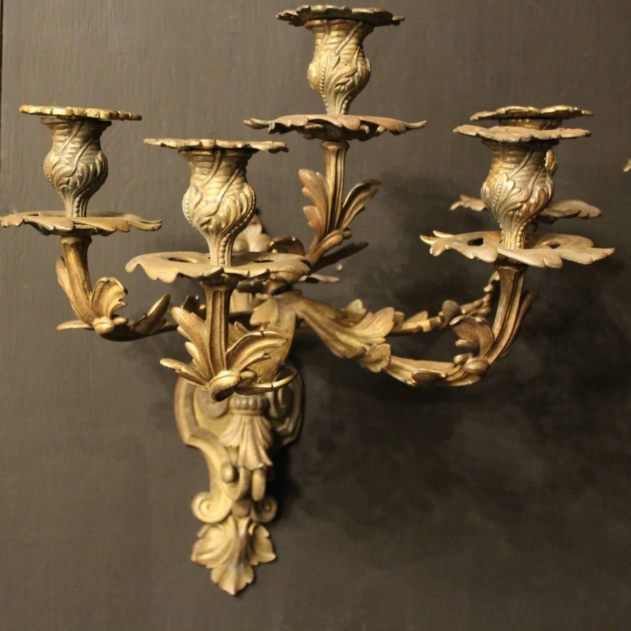 A pair of large French bronze five-arm antique candle wall sconces, the acanthus leaf scrolling arms with pierced leaf bobeche drip pans and bulbous leaf candle sconces, issuing from a decoratively cast backplate, original patination and well cast.