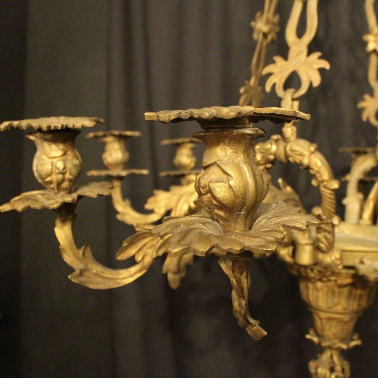 A French gilded bronze eight-light antique candle chandelier, the ornate acanthus leaf scrolling arms with leaf bobeches and floral candle sconces, issuing from a decorative Anthenion clad central urn with flame pierced tapering base, with the