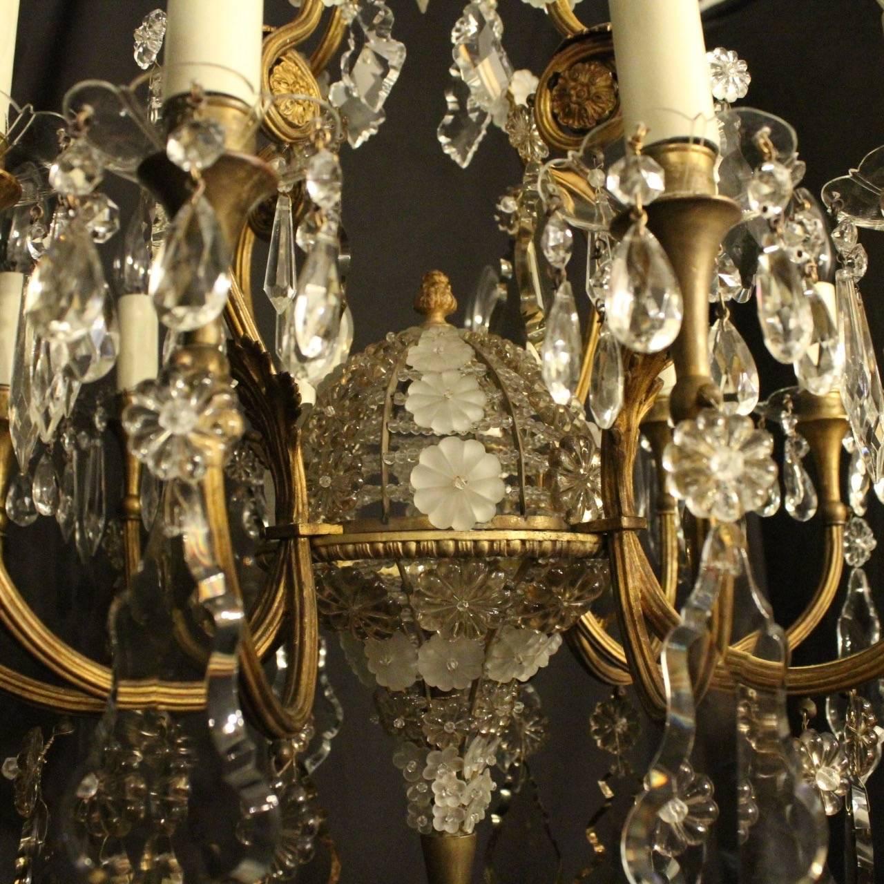 A French gilded cast bronze and crystal twelve-light birdcage form antique chandelier, the reeded scrolling arms with glass bobeche drip pans and candle sconces, issuing from a foliated cage form interior with ornate domed lattice work centre,