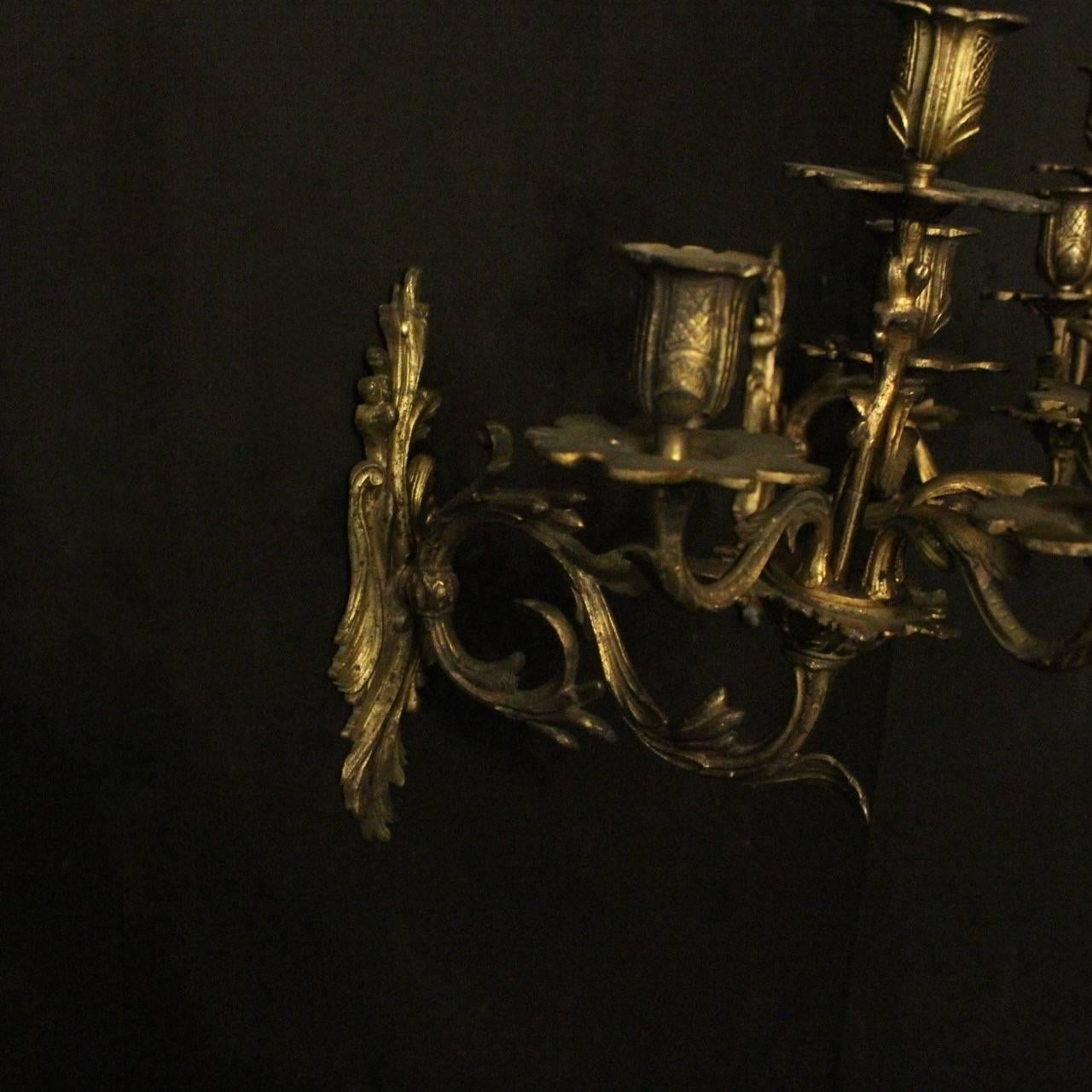 A French pair of gilded bronze five-arm double tiered antique candle wall sconces, the Acanthus leaf scrolling arms with leaf bobeches drip pans and decorative bulbous candle sconces, issuing from an ornately cast Acanthus leaf backplate, original