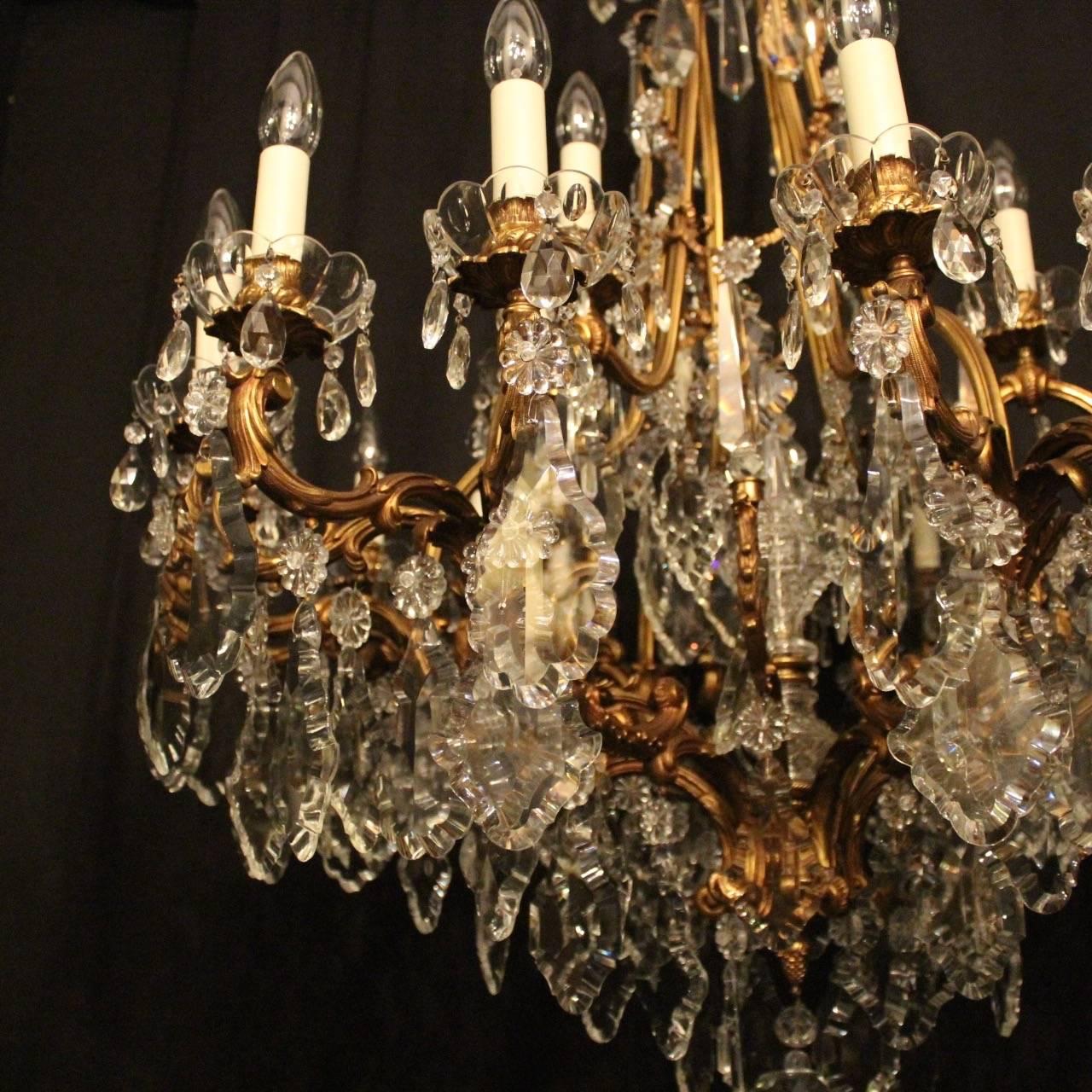 An ornate and large French gilded bronze and crystal twenty-four-light birdcage form double tiered antique chandelier, the foliated leaf scrolling arms with glass bobeches drip pans and bulbous leaf candle sconces, issuing from an elaborate cage