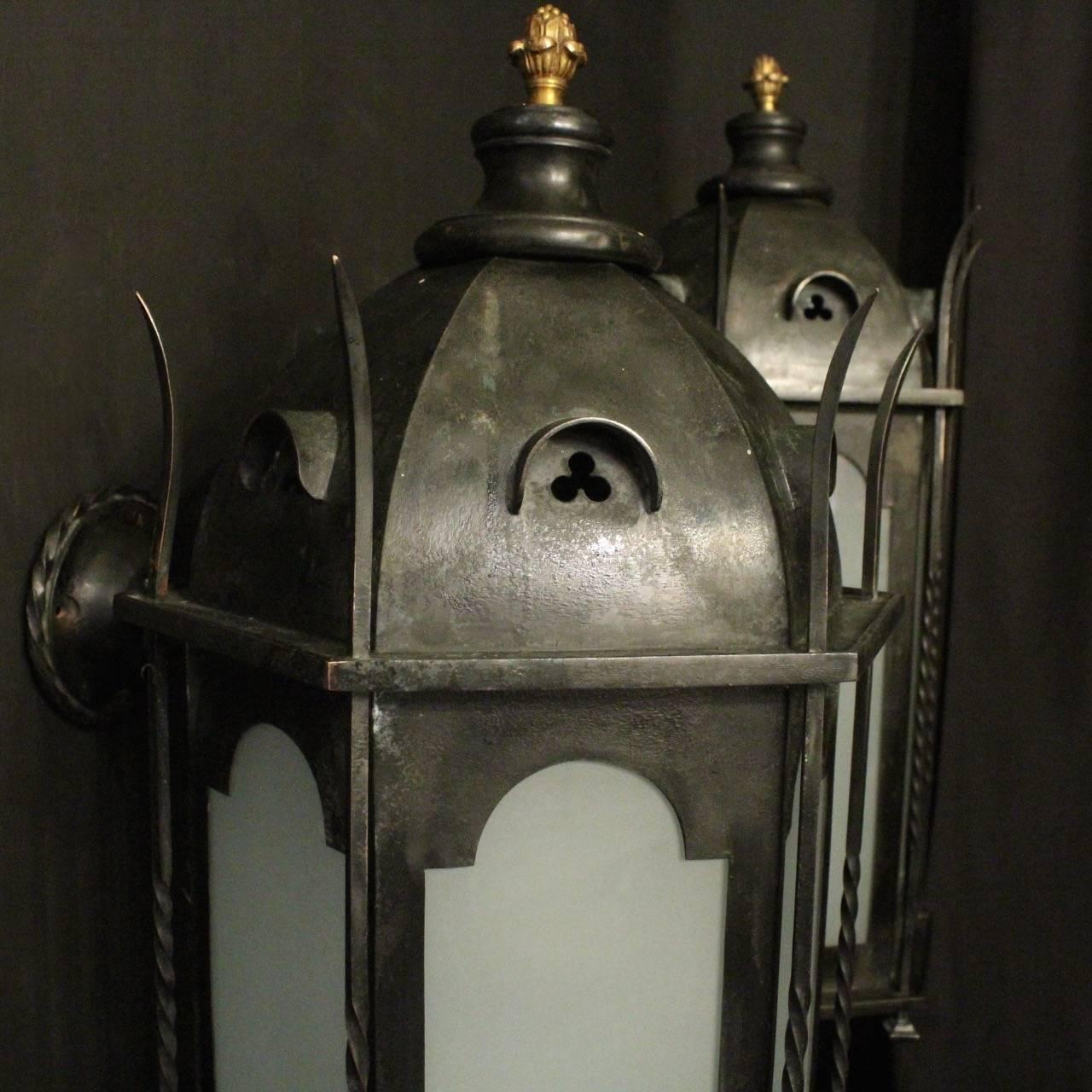 An English pair of Gothic single light bronze and copper external antique wall lanterns, the square gauge wall mounts issuing from a barley twisted circular backplate, the hexagonal domed frame surrounded by six frosted sectional glass panels which