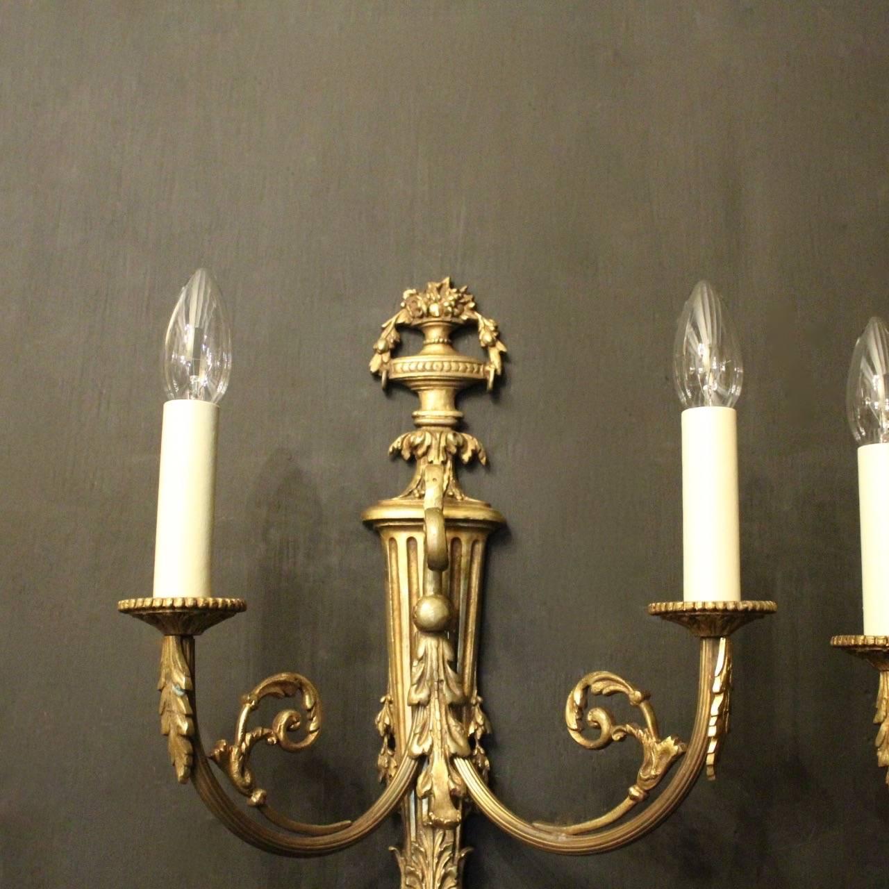A French pair of gilded bronze twin arm antique wall sconces, the reeded scrolling arms with leaf circular bobeche drip pans, issuing from an ornate reeded tapering backplate with pierced floral urn finial, good original gilded patination and nice