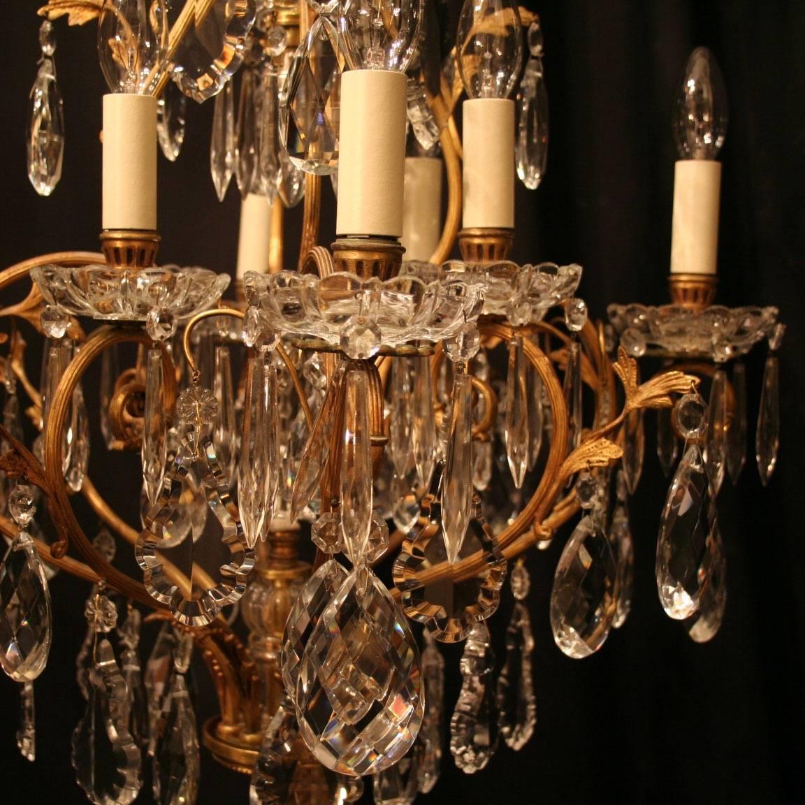 A French gilded cast brass and crystal nine-light birdcage form antique chandelier, the eight reeded scrolling arms with glass drip pans, issuing from a cage form interior with a single inverted light fitting and central prismatic spike, decorated