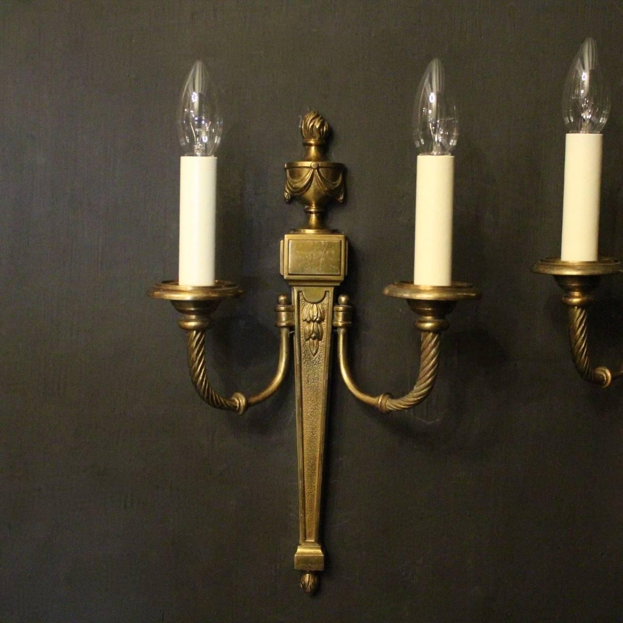 A French set of four gilded bronze twin branch antique wall lights, the barley twisted scrolling arms with circular bobeche drip pans, issuing from a tapering back plate with urn swaged finial, good original patination and great proportions. Fully