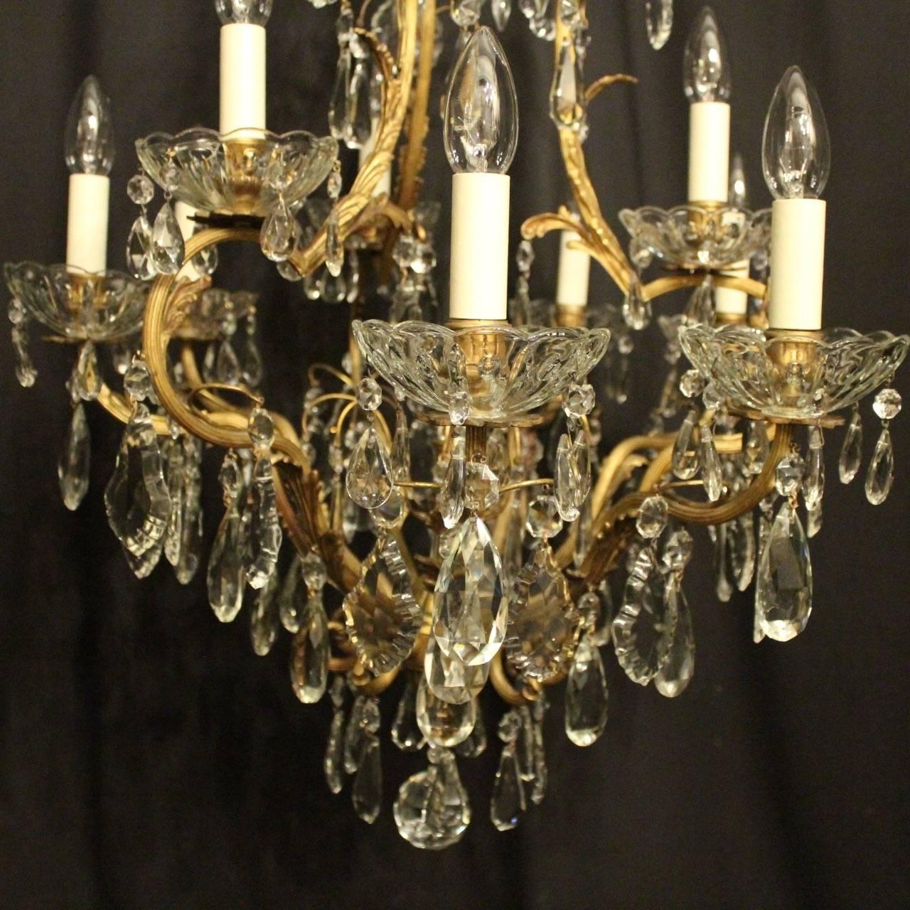 A French gilded bronze and crystal ten-light double tiered birdcage form antique chandelier, the nine reeded scrolling arms with glass bobeche drip pans and reeded candle sconces, issuing from an foliated cage form interior with a single inverted