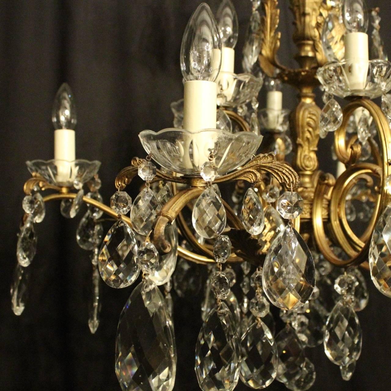 An Italian gilded cast brass and crystal twelve-light double tiered antique chandelier, the leaf scrolling arms with Acanthus leaf outcrops and glass bobeche drip pans, issuing from an ornately cast baluster central column and Acanthus leaf mid and