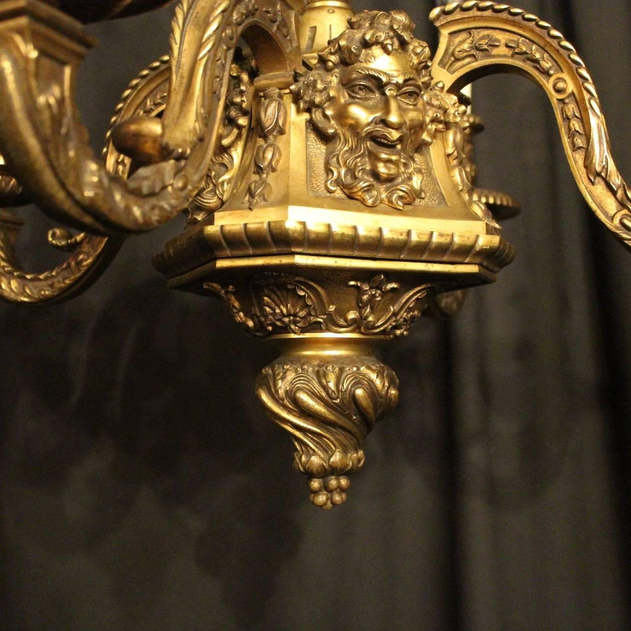 A French gilded bronze four-light Bacchic headed antique chandelier, the decoratively clad acanthus leaf square gauge scrolling arms with circular sectional leaf bobeche drip pans and bulbous leaf candle sconces, issuing from an ornate bulbous