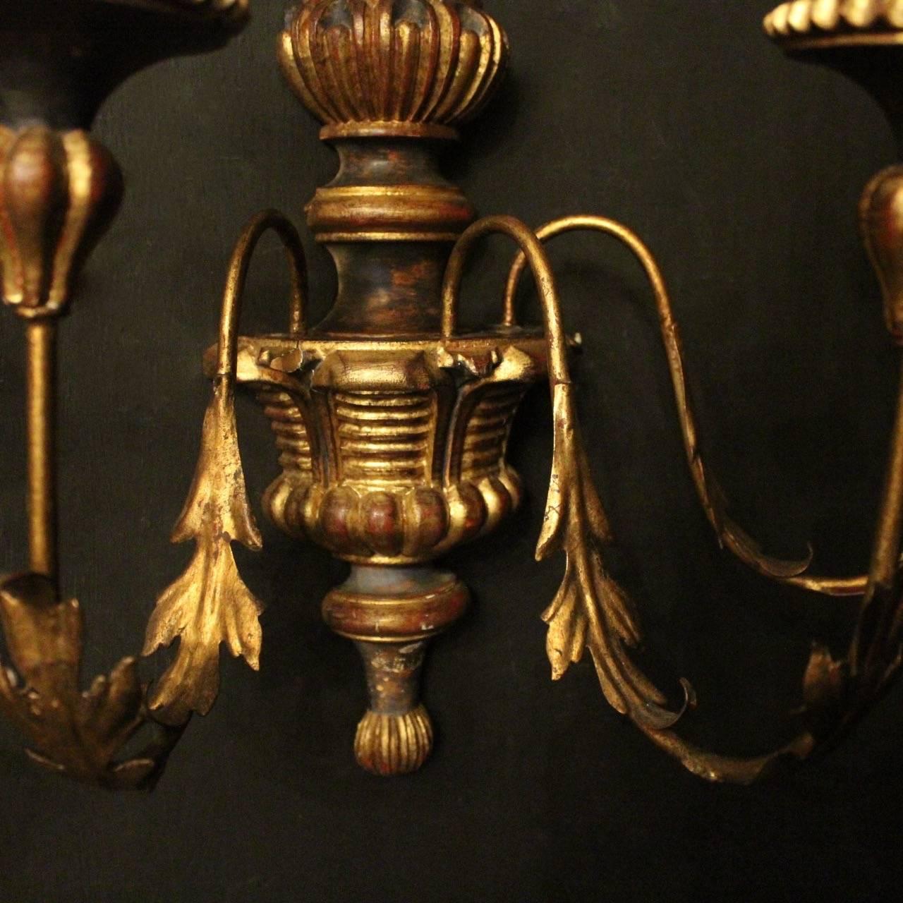 A decorative Italian florentine carved giltwood and toleware triple-arm wall lights, the foliated toleware acanthus leaf scrolling arms with wooden sectional bobeche drip pans and bulbous candle sconces, issuing from an ornate reeded bulbous wooden