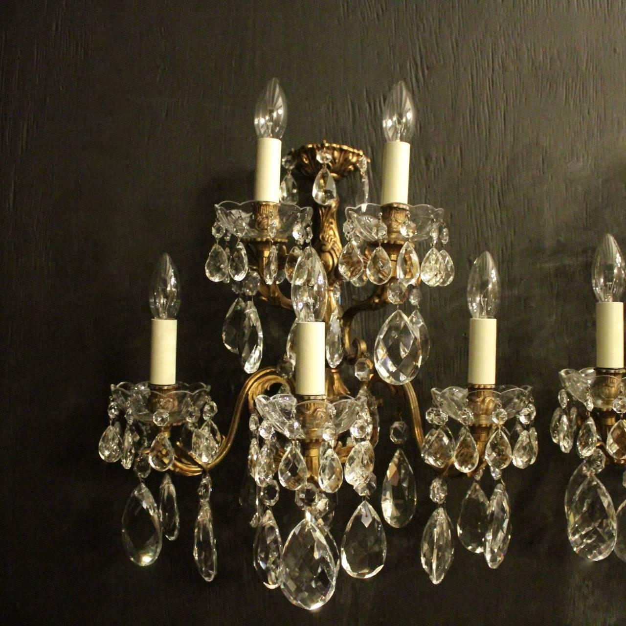 A large Italian pair of gilded cast bronze and crystal five-arm double tiered antique wall lights, the leaf scrolling arms with glass bobeches drip pans and bulbous leaf candle sconces, issuing from a foliated elongated backplate and decorated with
