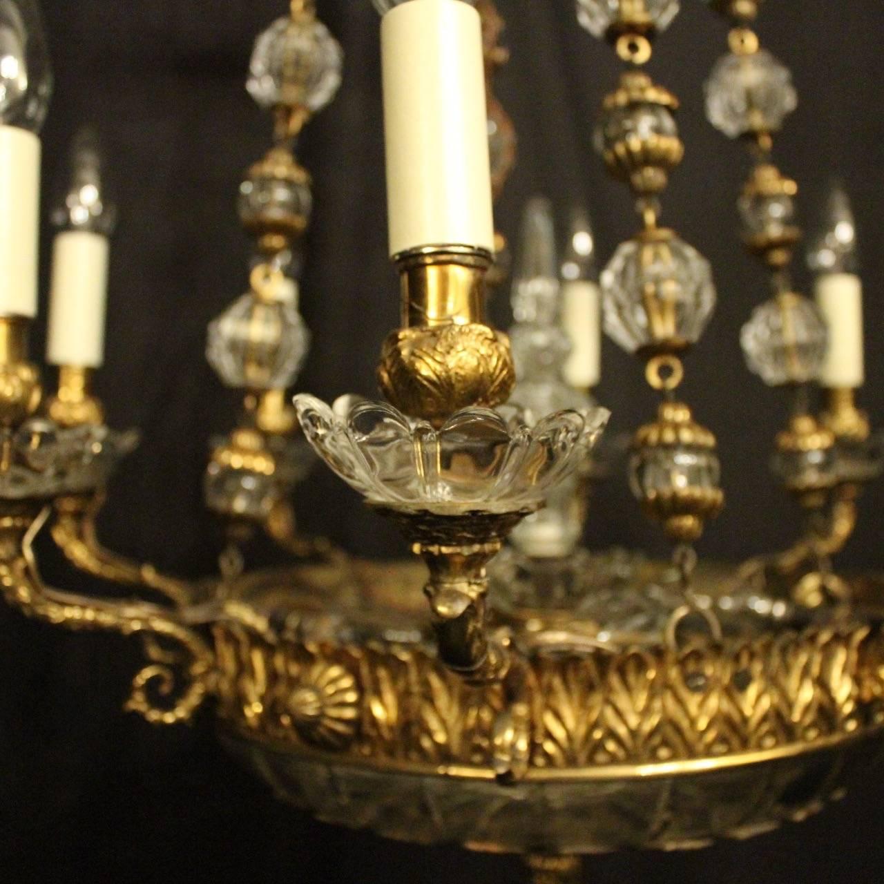 A lovely French gilded bronze 10 light antique chandelier, the 6 ornate leaf scrolling arms with foliated glass bobeche drip pans and bulbous candle sconces, issuing from a decorative leaf clad circular band with 4 internal light fittings, crystal