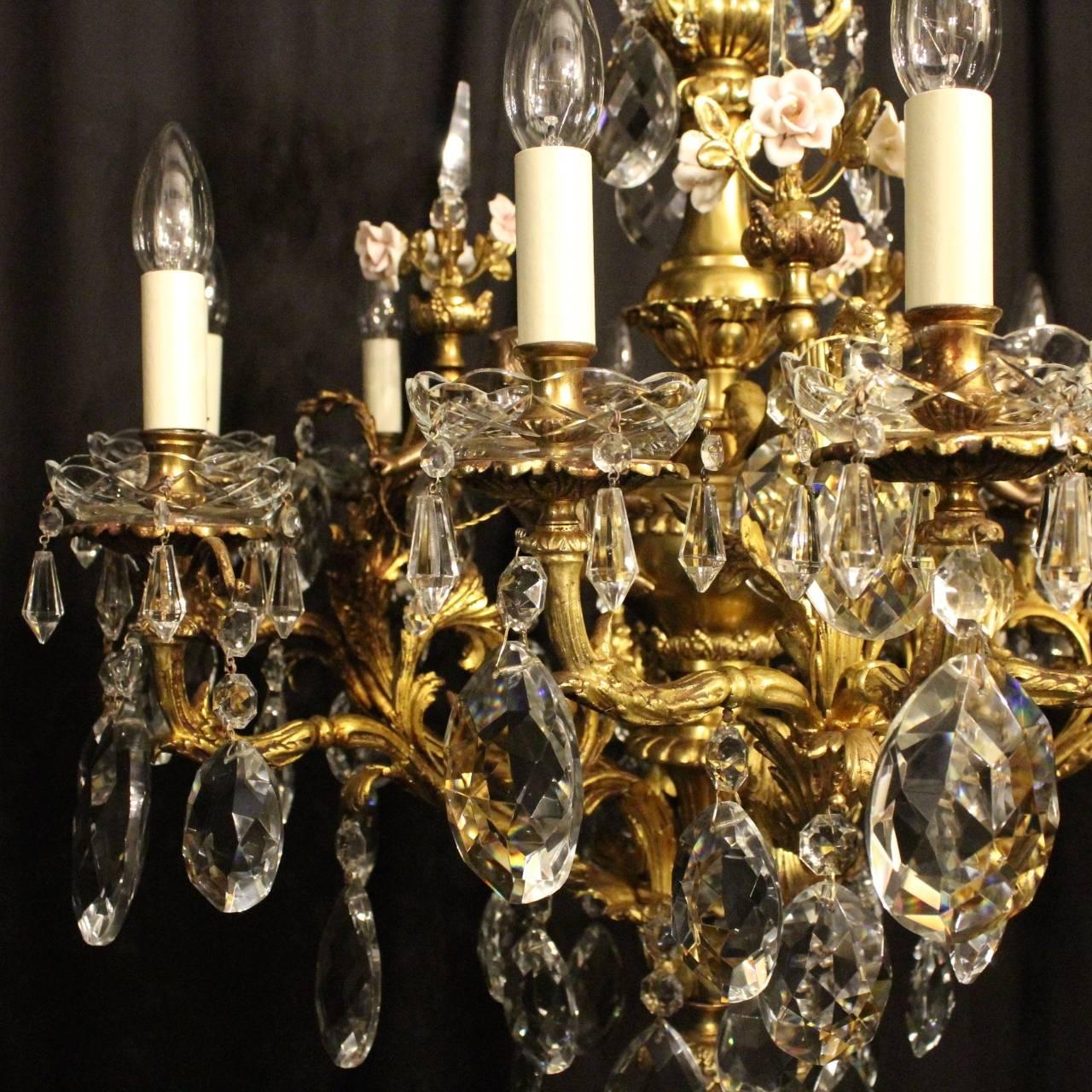 A French gilded cast bronze and crystal twelve-light cherub antique chandelier, the acanthus leaf scrolling arms with glass bobeche drip pans and bulbous candle sconces, issuing from an foliated interior with ornate bronze cherubs and porcelain