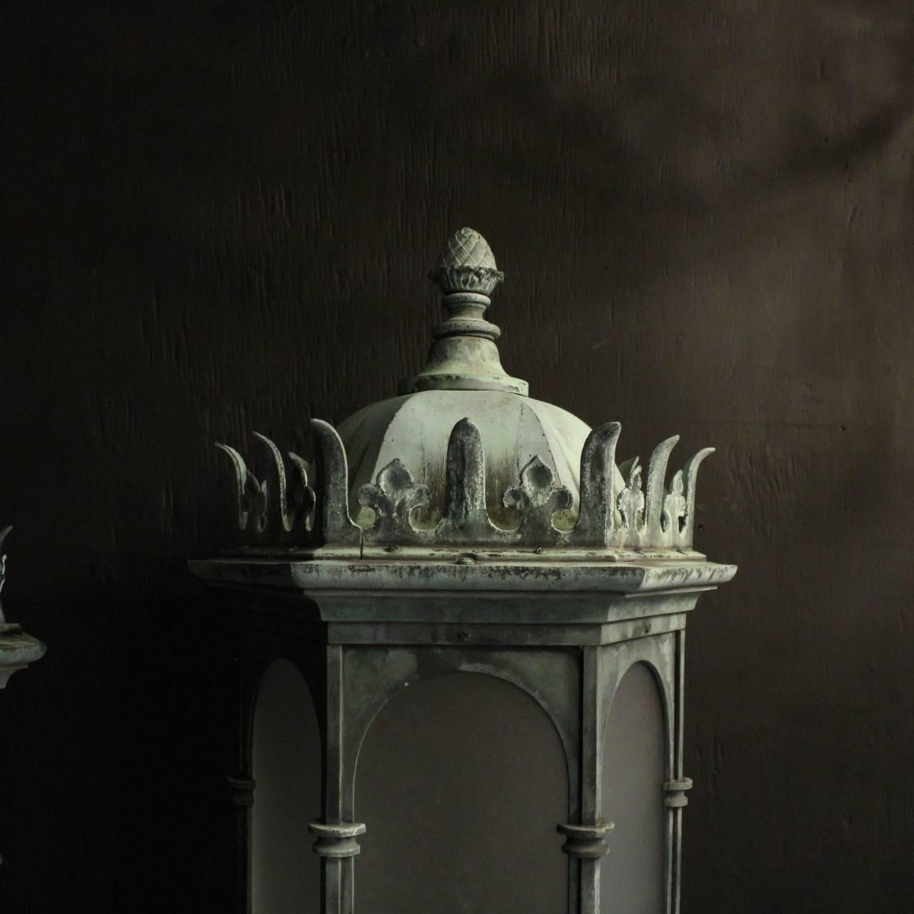 An English pair of Gothic single light bronze external antique wall lanterns, the scrolling acanthus clad arms issuing from an hexagonal backplate surrounded by six frosted sectional glass panels which are held within an ornate scrolling bronze