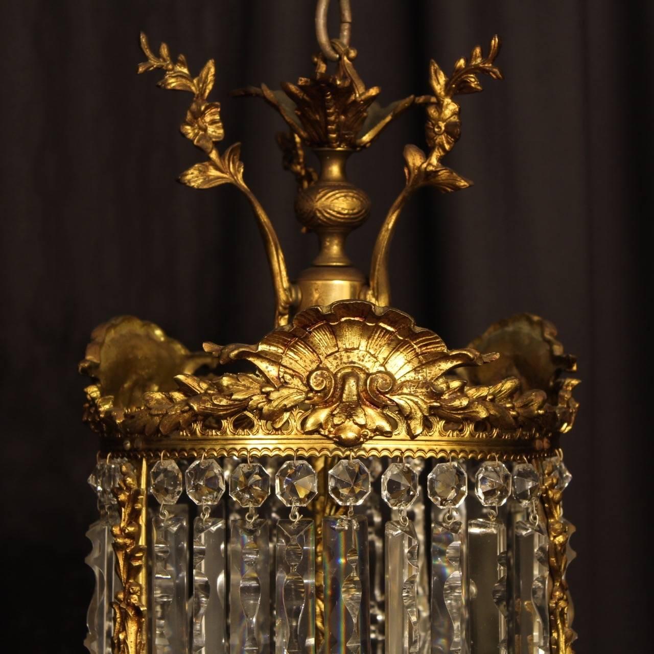 A quality French gilded bronze and crystal triple light antique lantern light, the three scrolling arms with foliated bobeche drip pans and bulbous candle sconces, issuing from a circular lantern form interior, decorated overall with faceted crystal