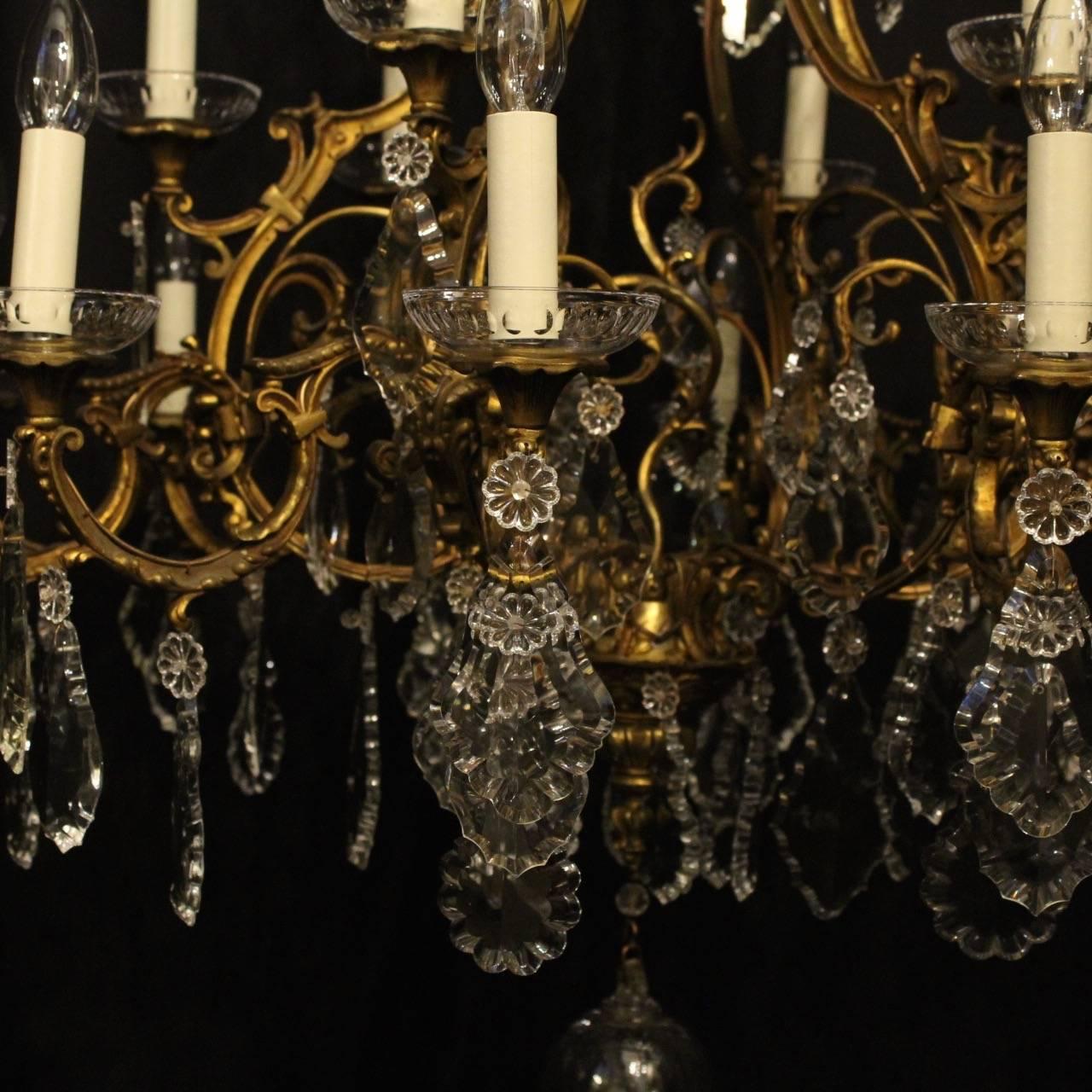 French gilded cast bronze and crystal eighteen-light double tiered antique chandelier, the leaf scrolling arms with glass bobeche drip pans, issuing from an foliated cage form interior with an elaborate leaf canopy and decorated overall with crystal