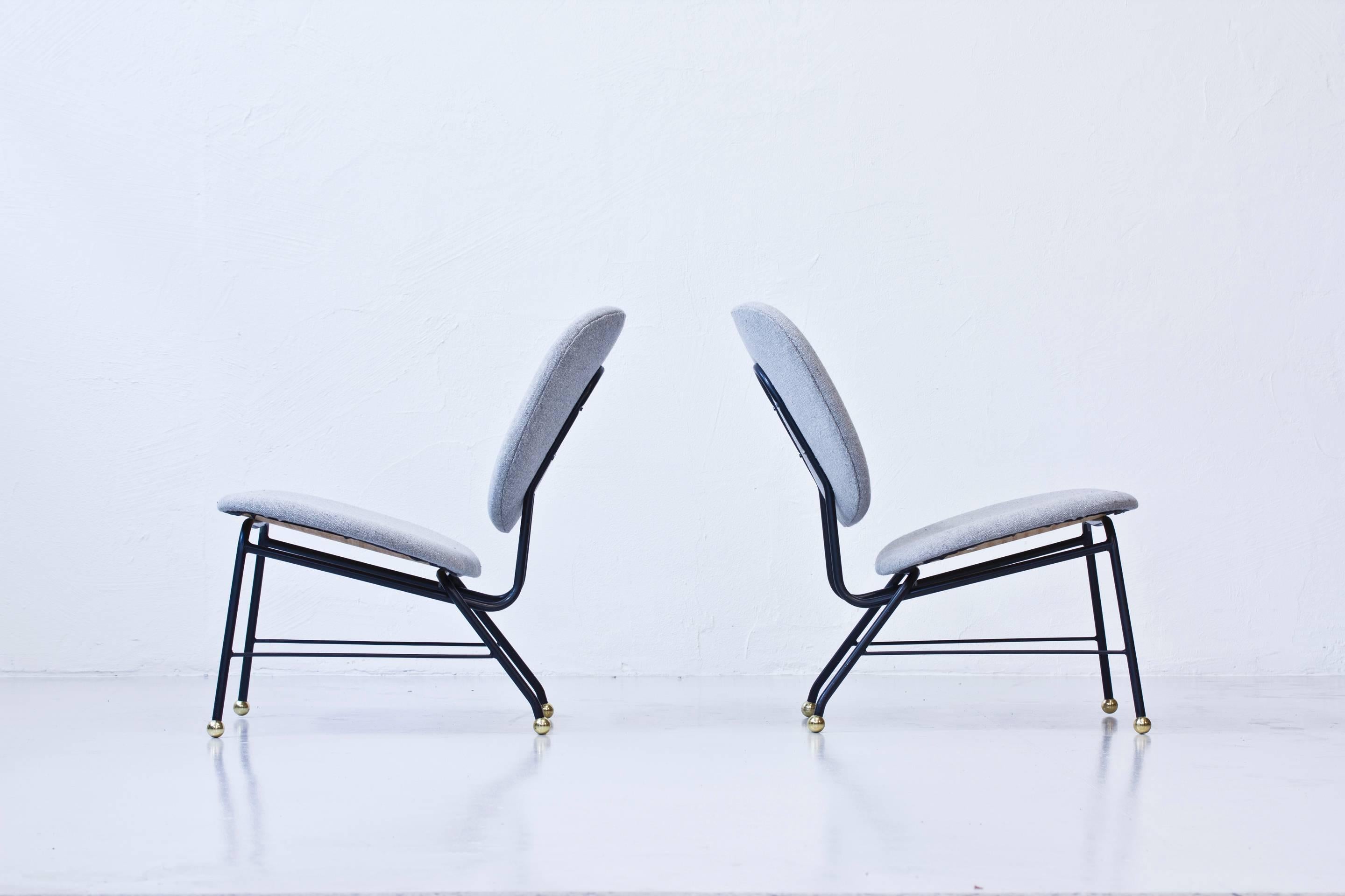 Rare pair of easy chairs produced in Sweden during the 1950s. Most likely designed by Alf Svensson and produced by Ljungs Industrier. Black lacquered metal frame with grey wool upholstery and large round brass feet. Excellent condition.
     