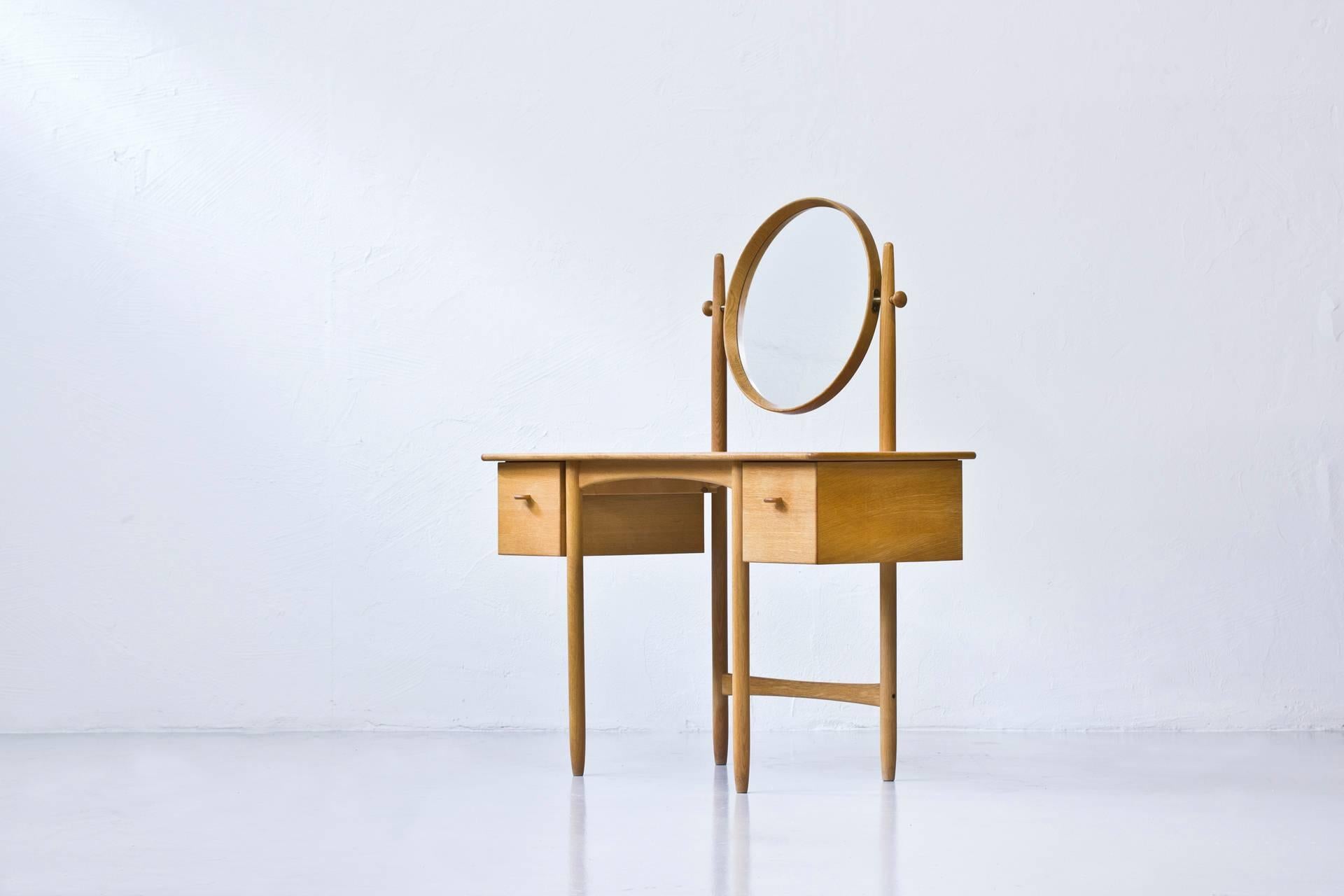 Rare dressing table designed in Sweden by Sven Engstrom & Gunnar Myrstrand. Produced by Bodafors in 1964. Solid oak base, drawers and mirror with oak table top and brass details. Original red lacquered tray on the inside of one of the drawers. Very