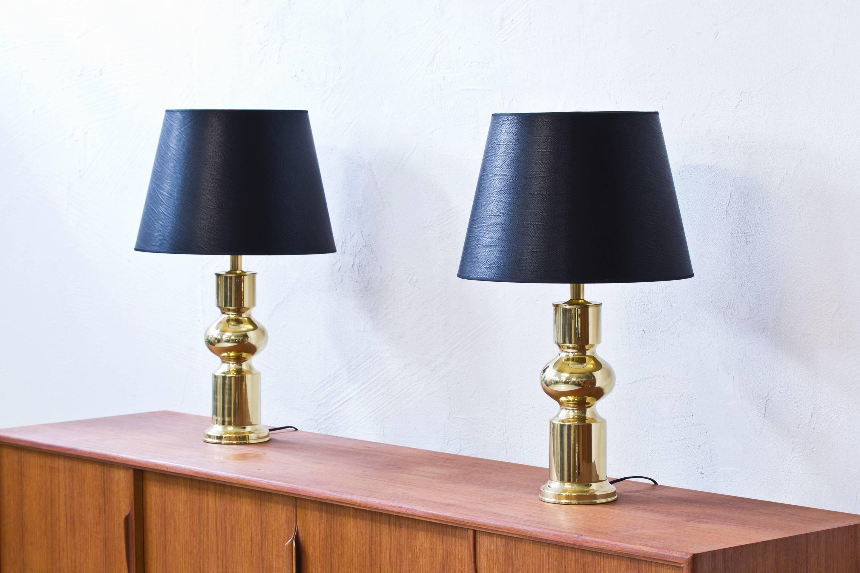 Pair of brass table lamps produced by Swedish company Aneta during the 1960s. With black lamp shades with crocodile impressed pattern and brass imitating inside for a warm glow. Light switch on the fixture in working condition. New electricity.