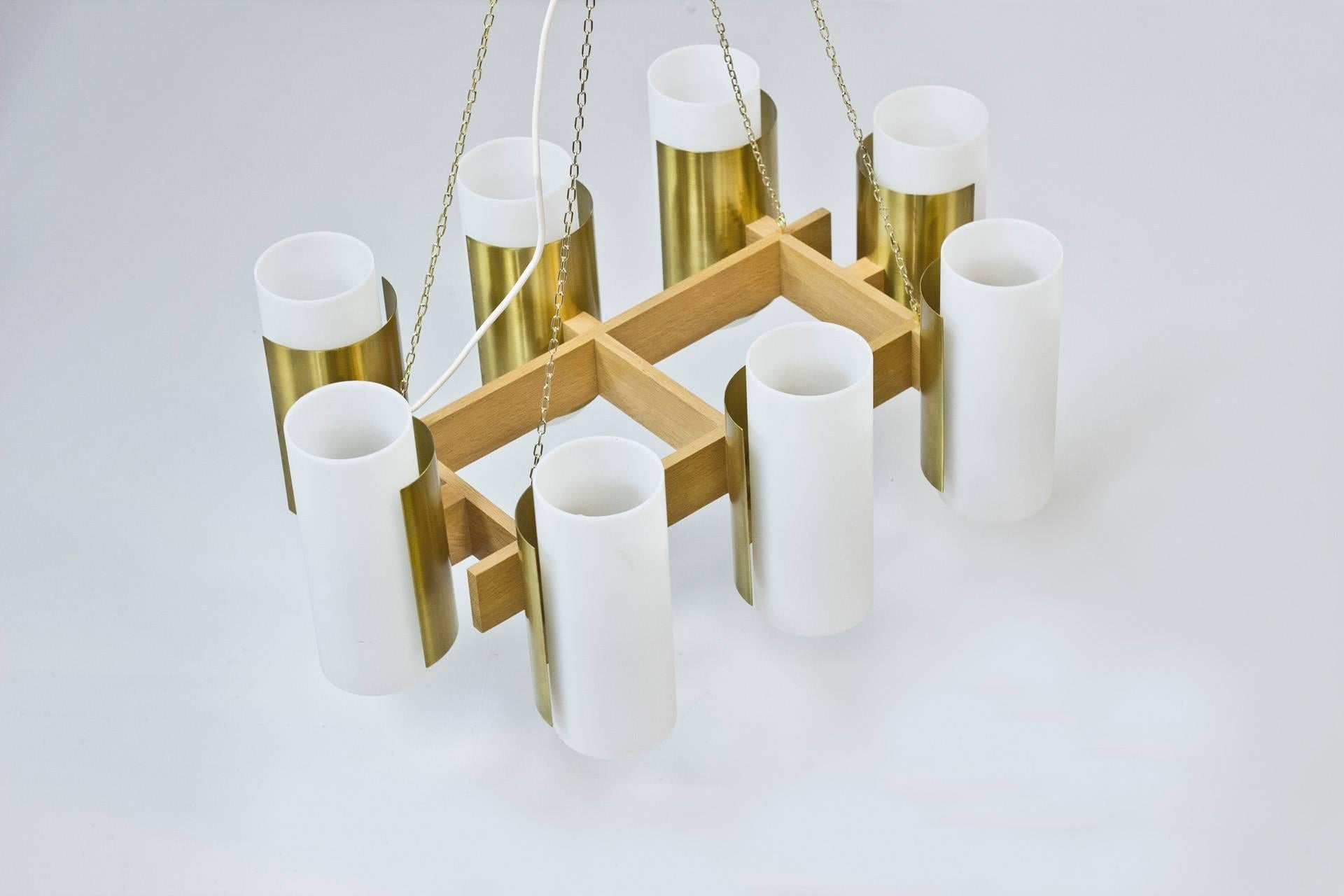 Unique set of four chandeliers designed by Sten Carlquist during the 1950s. Solid oak with dull polished brass diffusers and acrylic shades. Only remaining set from 