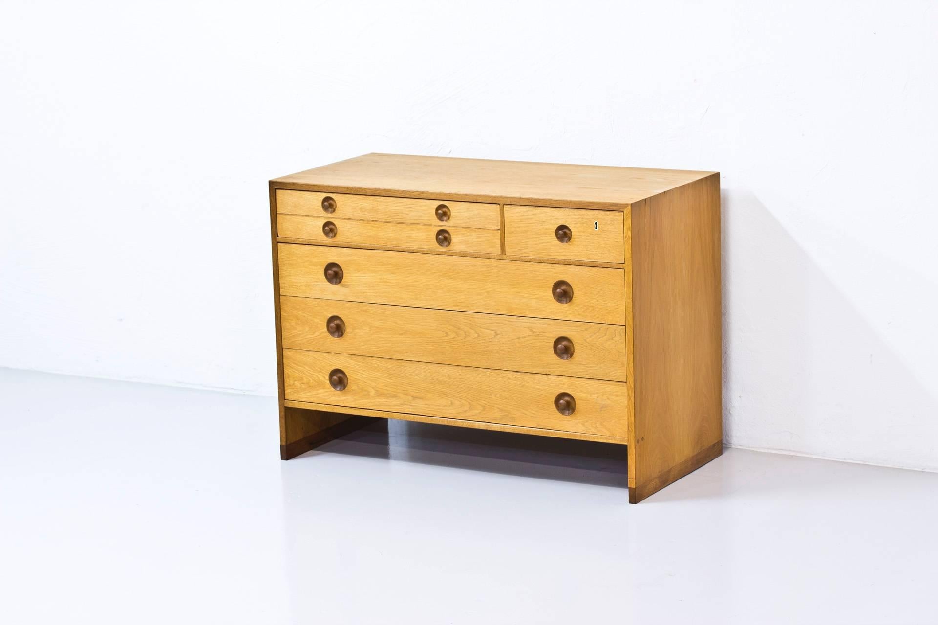 Chest of drawers designed by Hans J. Wegner. Produced in Denmark by Ry Mobler during the 1960s. Made from oak with handles and runners in red oak. Top right drawer with lock and key. The two top left drawers with green felt fabric on the inside.