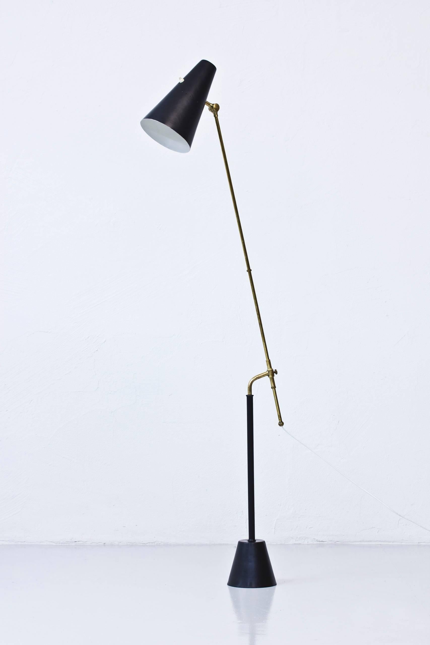 Rare floor lamp designed by Hans Bergstrom. Produced by his own company Atelje Lyktan in Sweden during the 1950s. Black lacquered metal and brass with original patina. Adjustable in height and adjustable shade. Light switch on top of the shade in