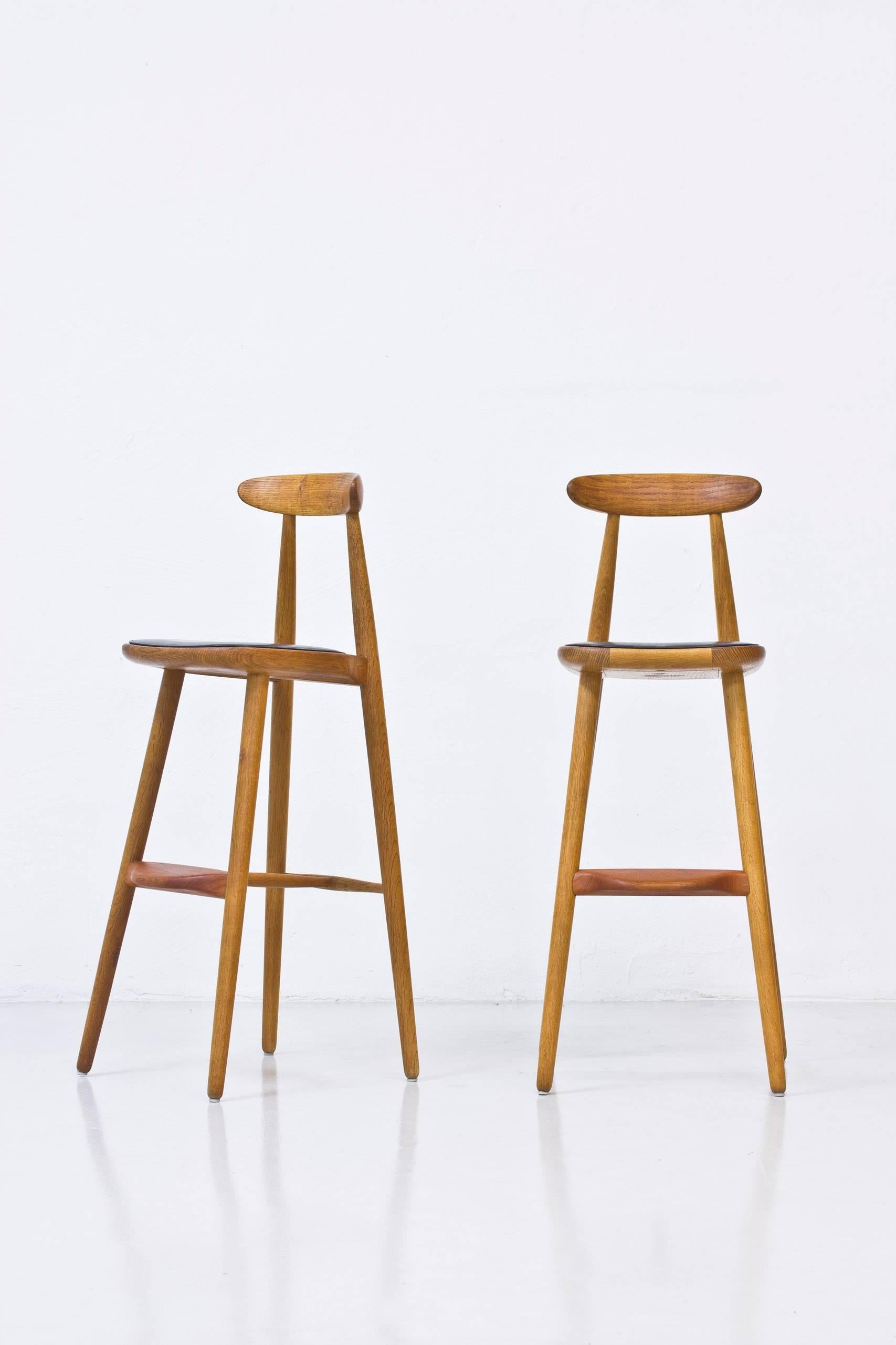 Very rare bar stools designed by Danish architect Wilhelm Wohlert. Produced in Denmark by Stolefabriken in Odense during the 1950s. Solid oak with teak footrest and original black leather seats. Excellent original condition with very few signs of