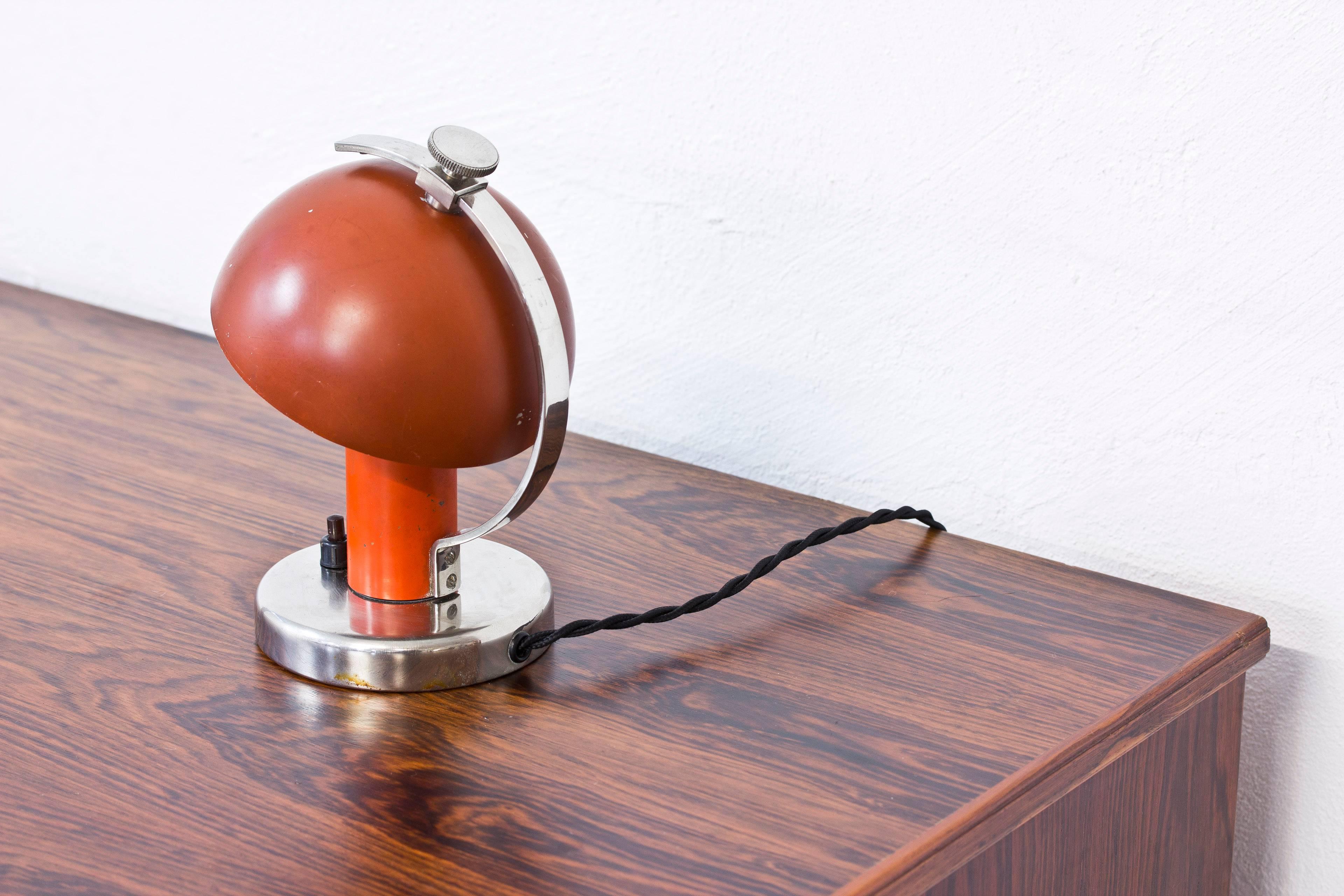 Small functionalist wall or table lamp designed by Erik Tidstrand. Produced in Sweden by Nordiska Kompaniet, NK during the 1930s. Made from nickel-plated metal and lacquered metal in two-tone orange/red. Adjustable shade for varying the light after