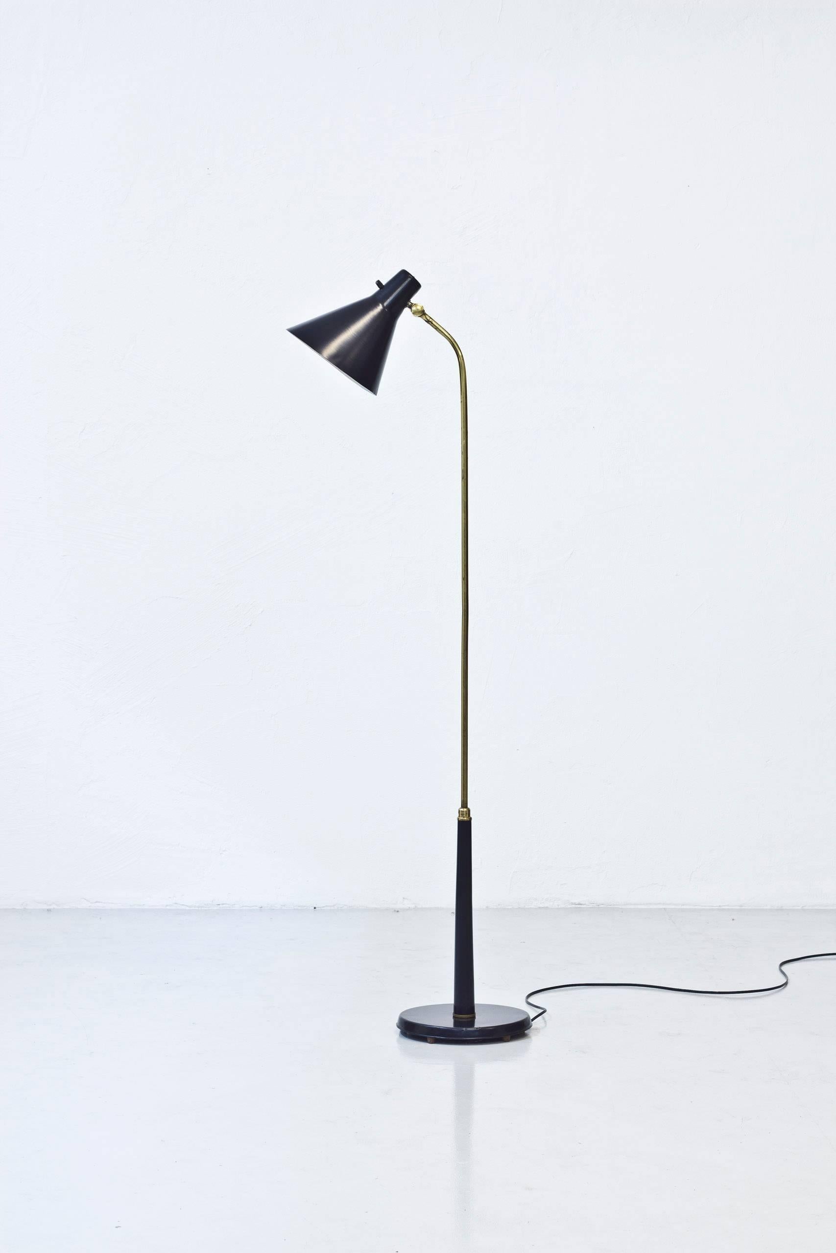 Floor lamp produced in Sweden by Nordiska Kompaniet during the 1950s. Most likely designed by their head of  design at the lighting department, Bertil Brisborg. Polished brass and black lacquered metal. Original light switch on top of the shade in