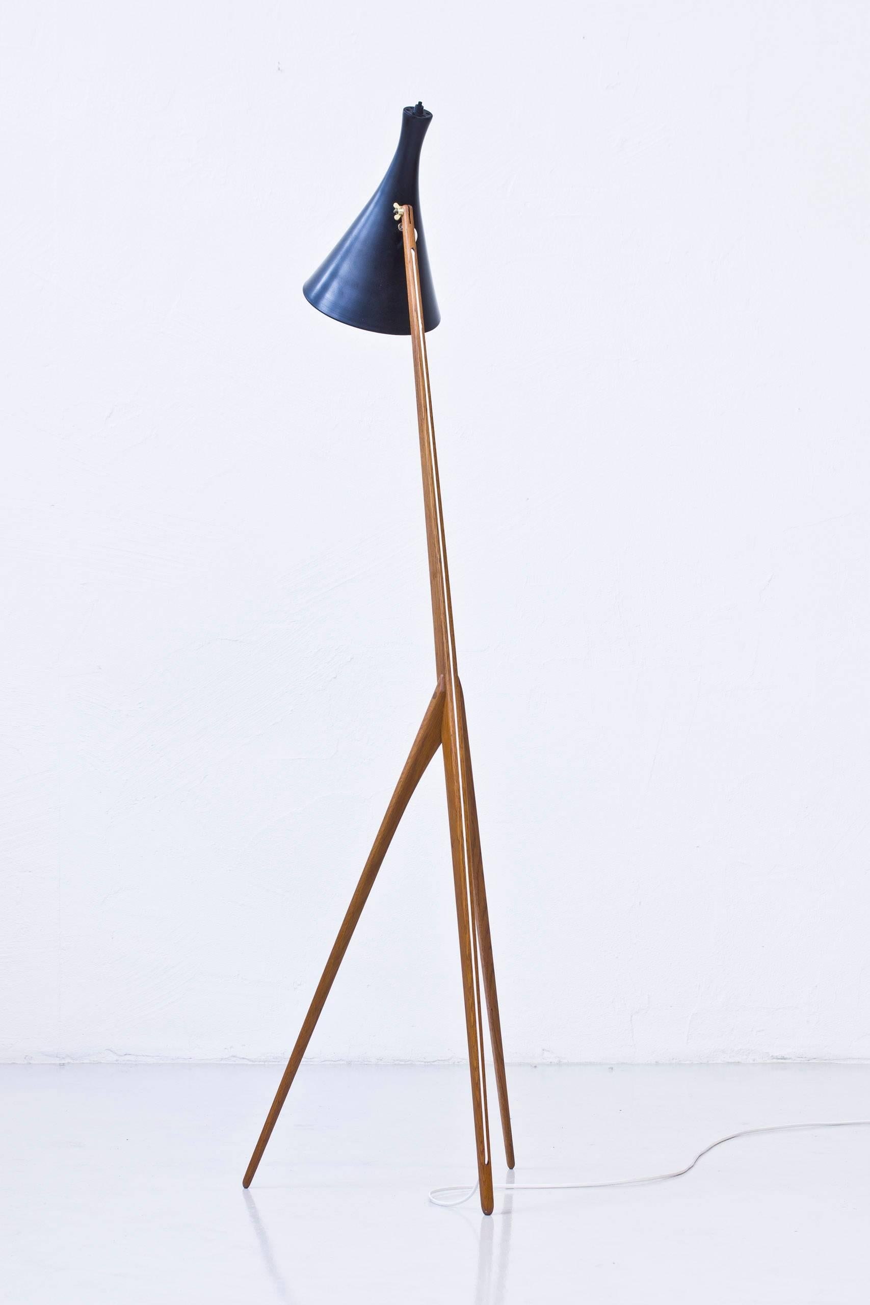 Rare floor lamp model Giraffe designed by Uno & Osten Kristiansson. Made by their own company Luxus in Vittsjo, Sweden during the 1950s. Solid oiled oak frame with brass details and aluminum shade in black and white lacquer. New chord. Light switch