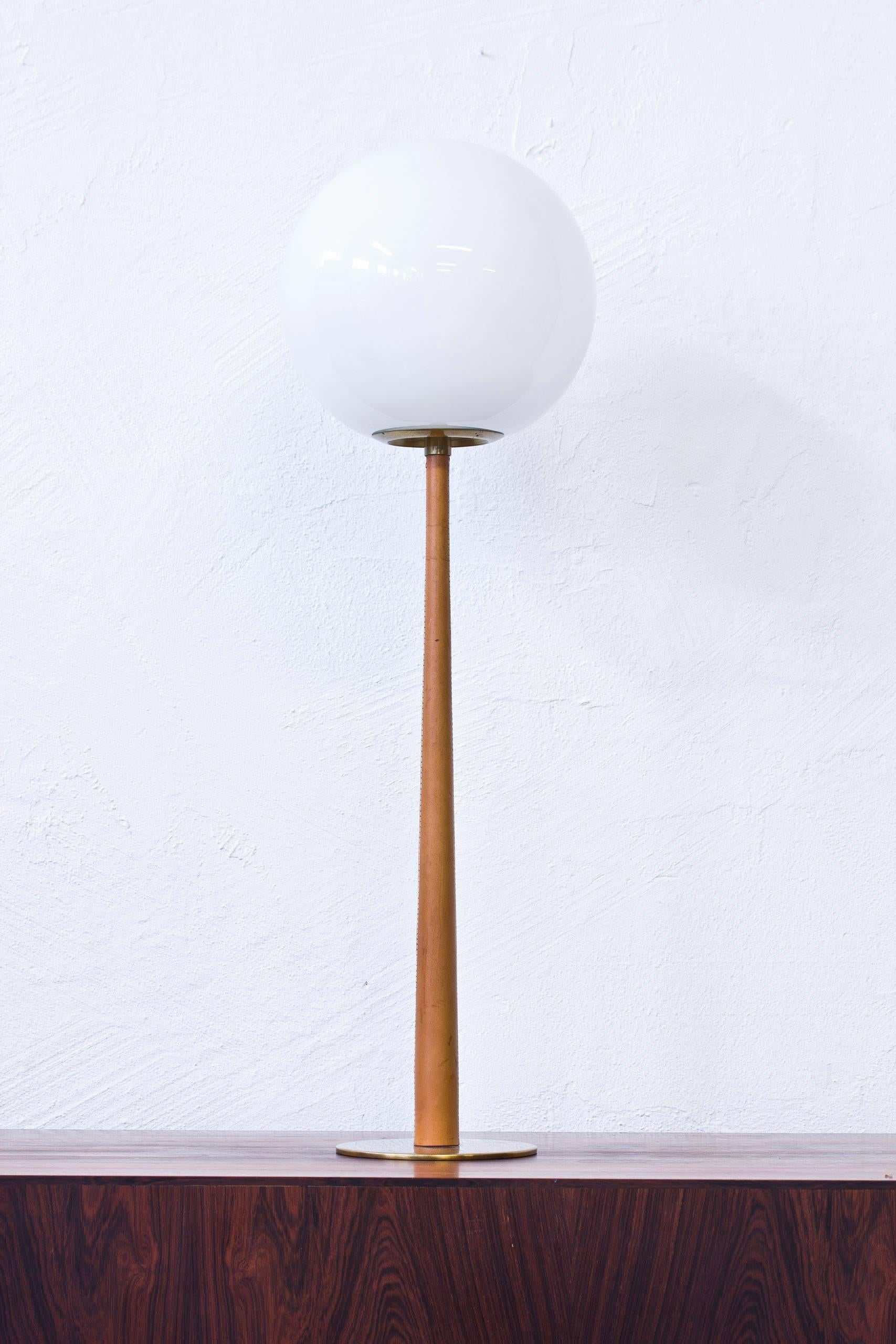 Rare table lamp model B 101 designed by Hans-Agne Jakobsson. Produced by his own company in Markaryd, Sweden during the 1960s. Solid polished brass base with leather wrapped stem and a large opaline glass shade. Light switch on the chord. Excellent