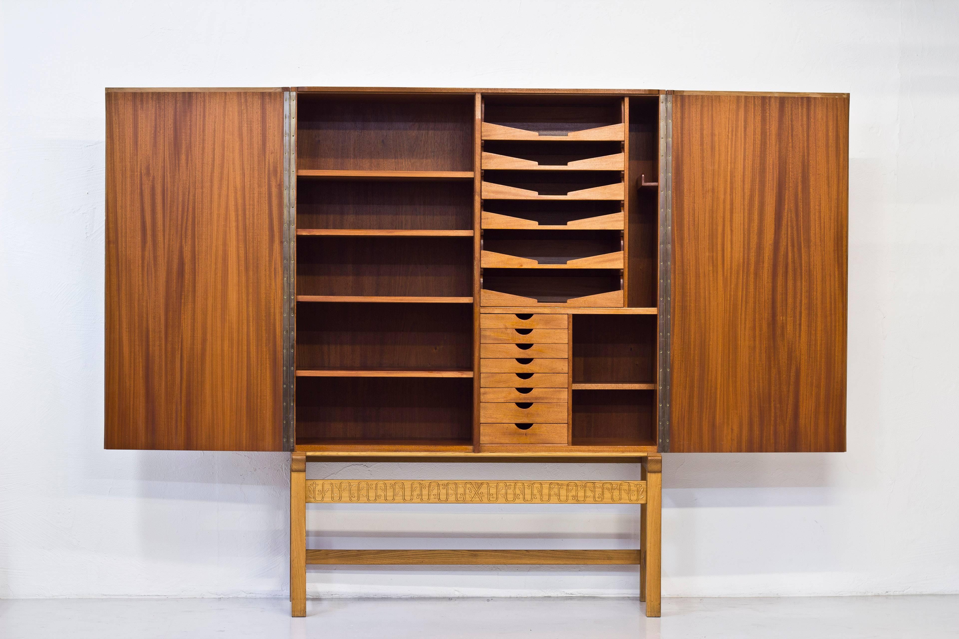 Unique cabinet designed by Architect David Nilsson and performed by master cabinet maker Gustaf Bouvin in 1942.  Massive cabinet standing on a base of solid oak with the outside of the cabinet made from pear wood. Inside in mahogany with adjustable