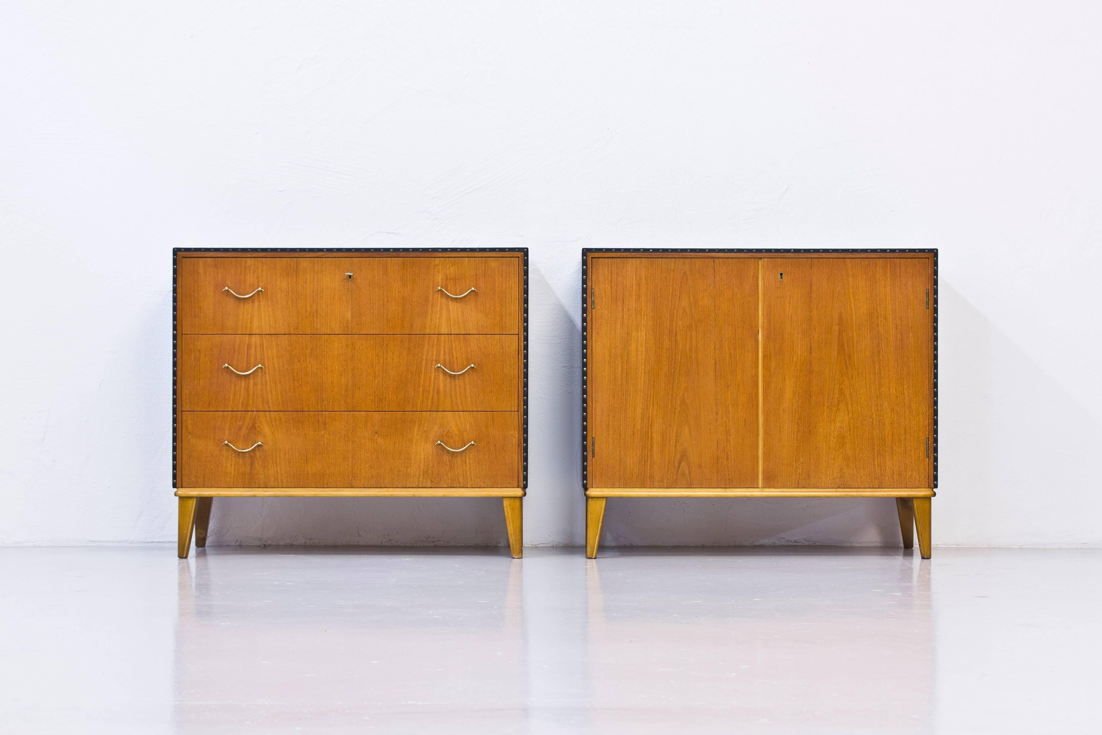 Matching chest of drawers and small cabinet in the style of Swedish designer Otto Schulz. Done in Sweden during the 1940s. Both cabinets with teak on back and the front doors/drawers. Tops and sides upholstered with dark blue faux leather with brass